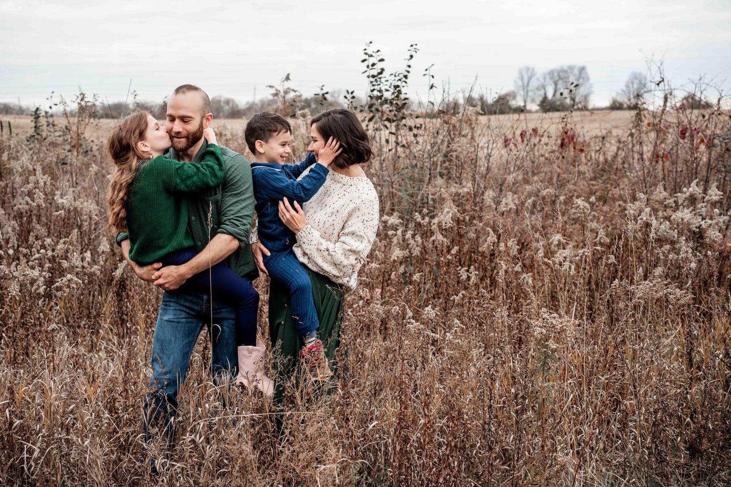 Family members walking together through tall grass in a rustic field setting.