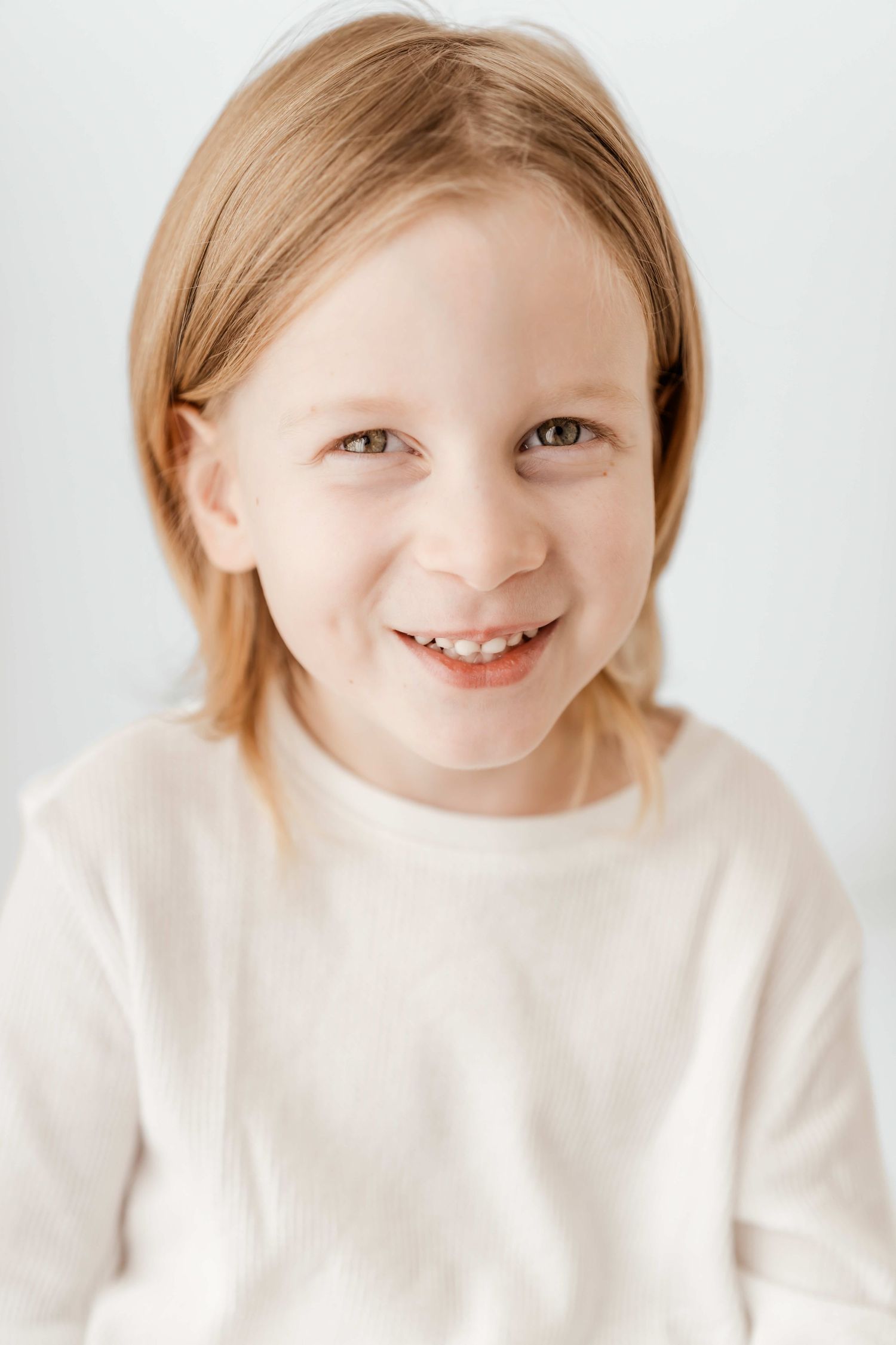 A series of four photos showing a child in a white sweater with a bright smile against a light background.