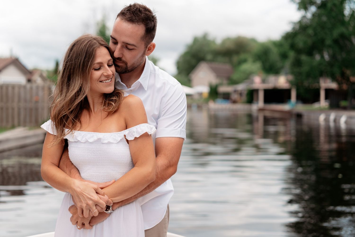 A couple shares tender moments together by a waterfront dock during a romantic summer photoshoot.