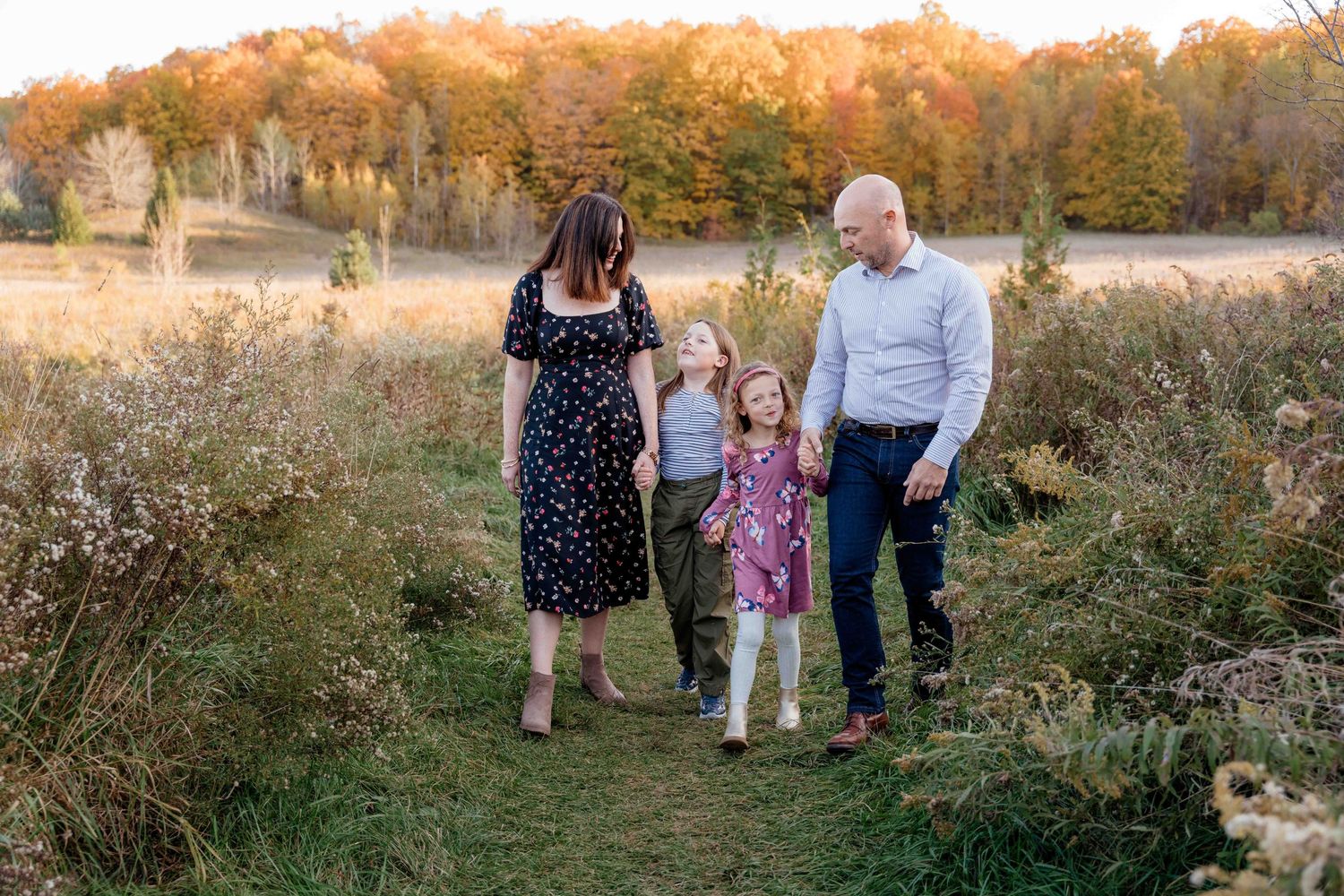 A group stands in a golden autumn meadow during sunset while wildflowers and tall grasses sway in the breeze.