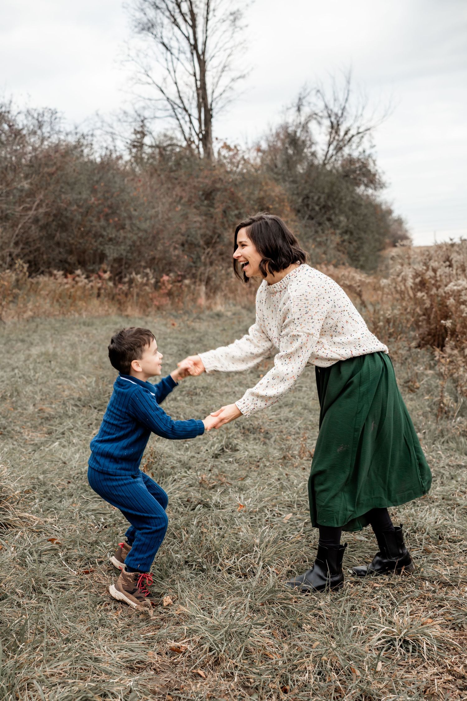 A series of playful outdoor moments showing a child in blue and a person in green skirt dancing together in a field.
