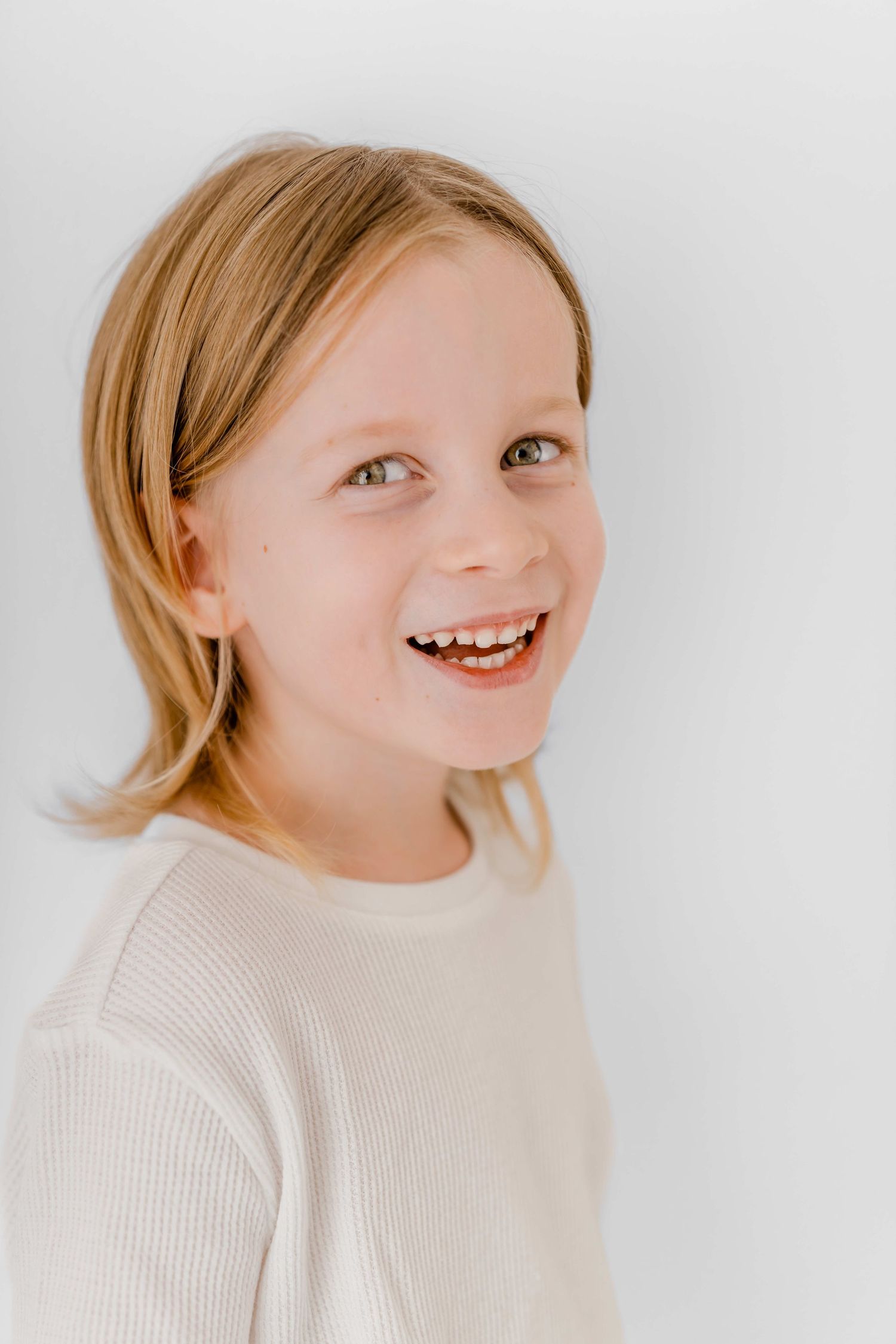 A series of four candid portraits showing joyful expressions and natural laughter against a light background.