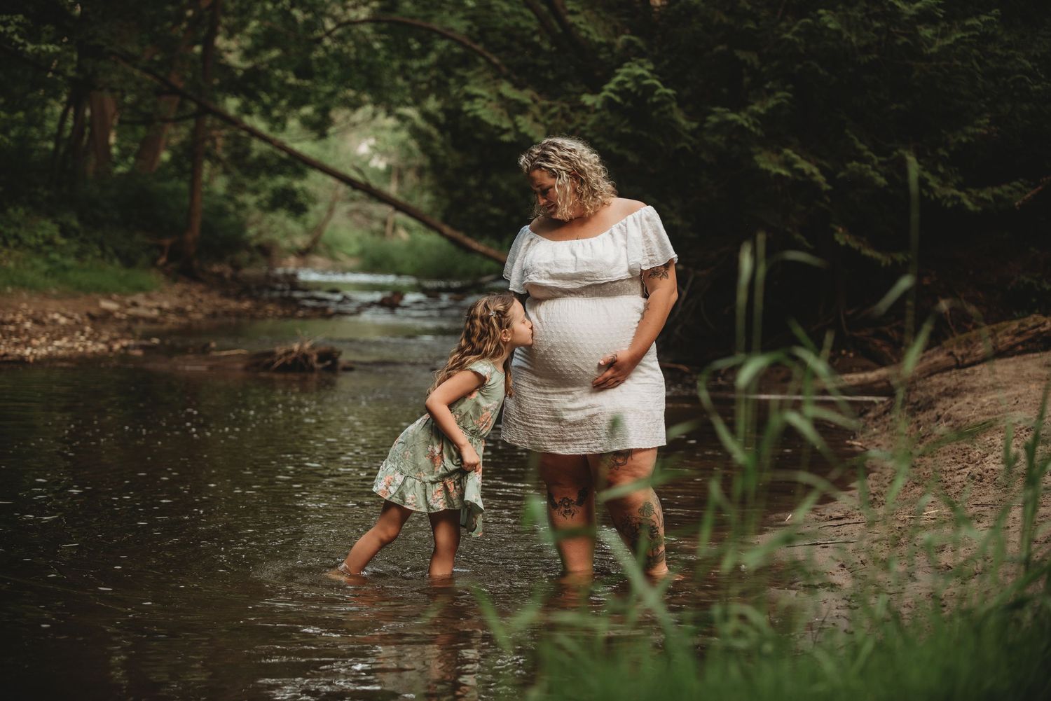 A tender moment captured at a creek as two people fish together on a peaceful summer afternoon.
