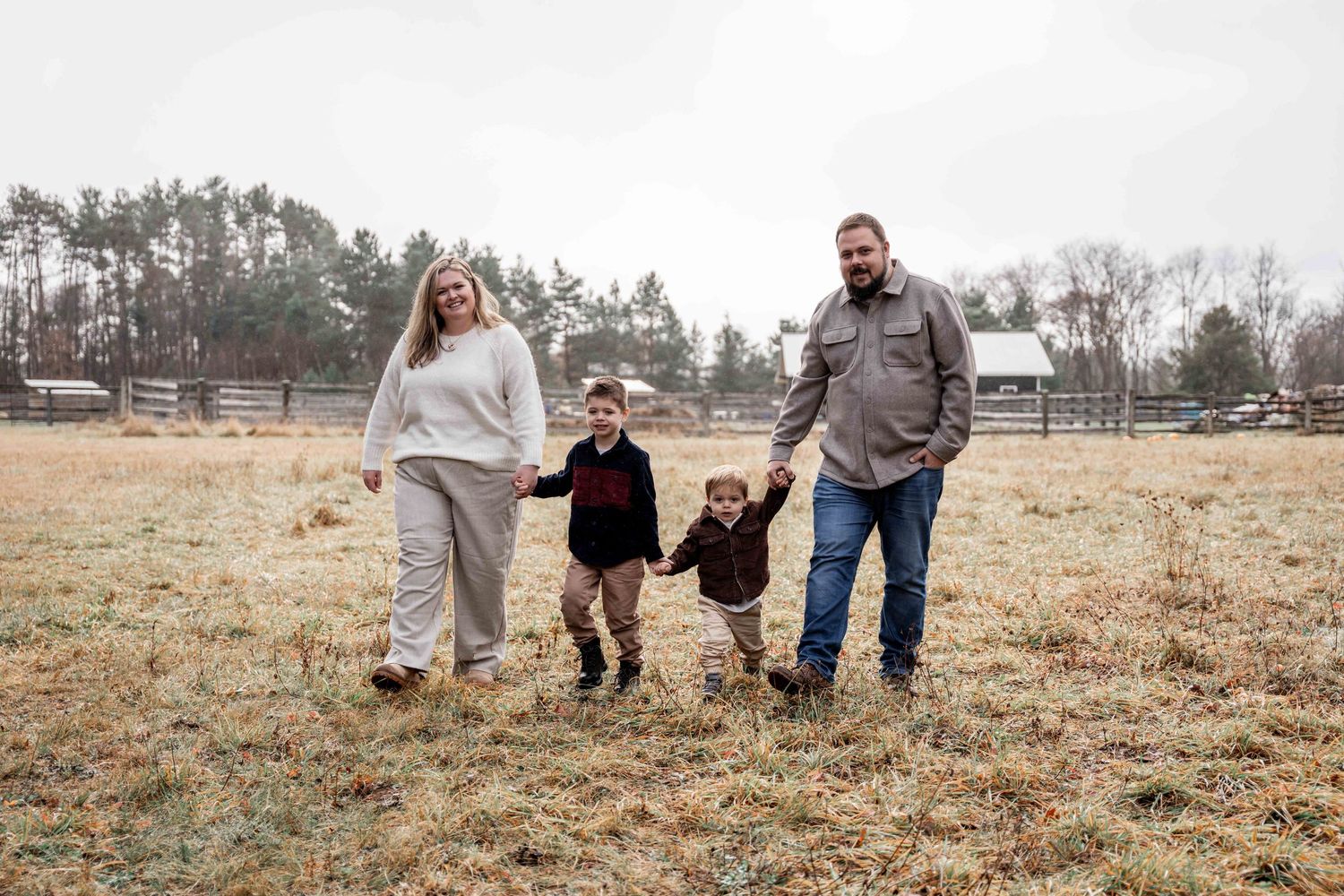 Family walking together through a golden autumn field during a lifestyle photography session.