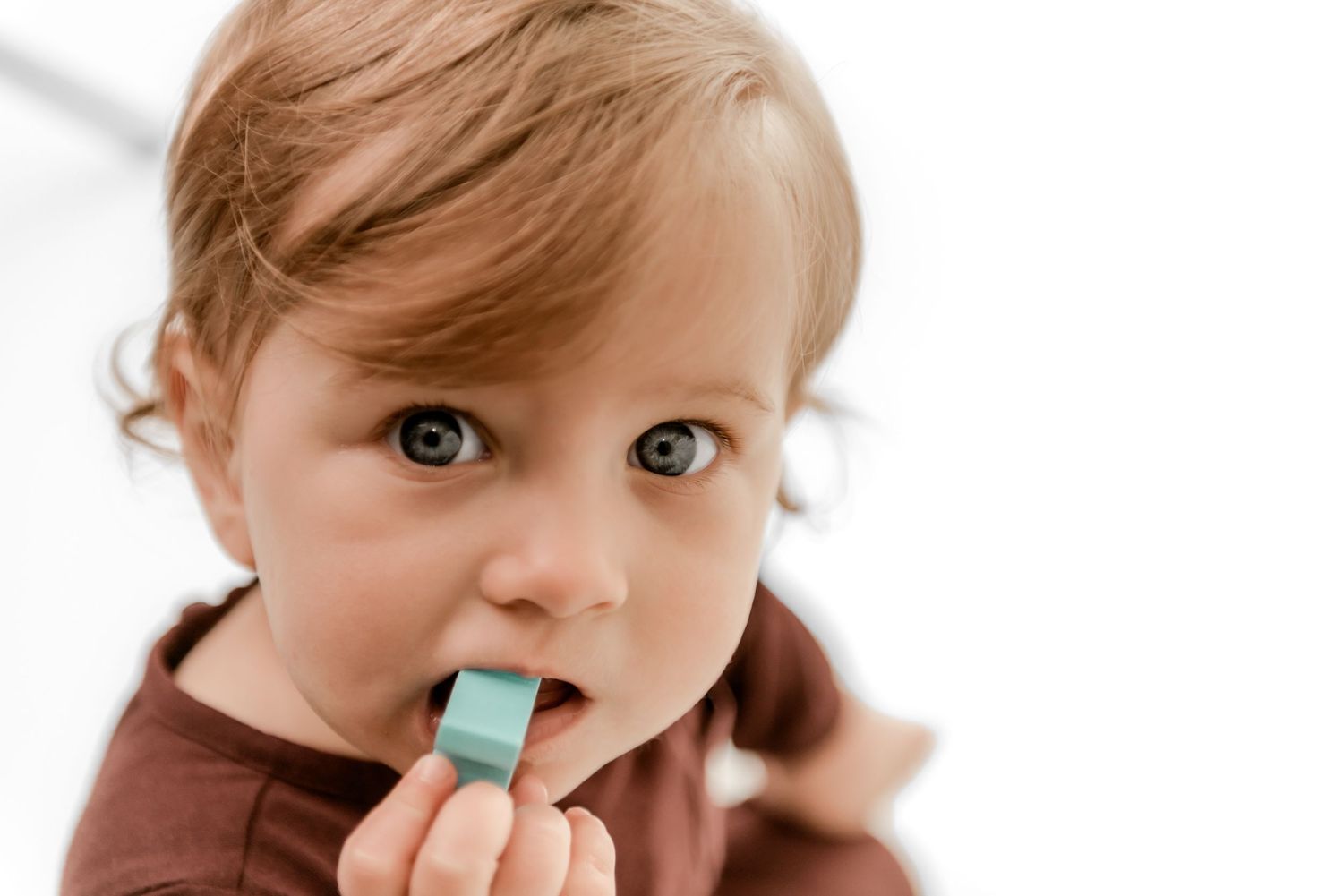 Four sequential photos showing a child eating a blue ice pop treat, with expressions of enjoyment and surprise.