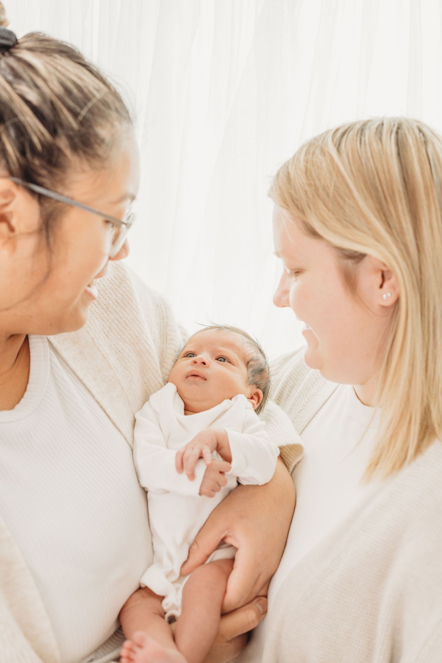 A tender series of photos showing a mother breastfeeding her newborn baby in a bright, minimalist setting.