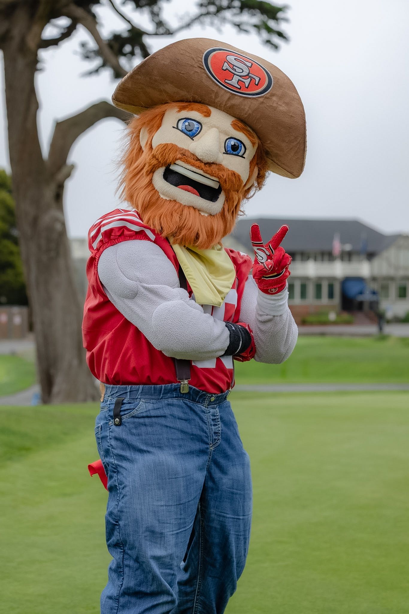 San Francisco 49ers mascot Sourdough Sam poses on a golf course giving a peace sign.