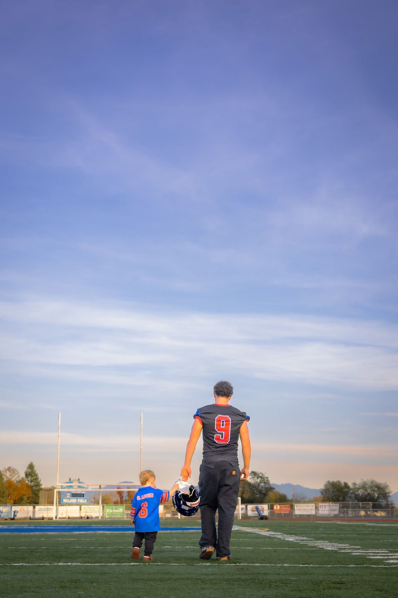 Analy high school senior walking with baby in football in portrait by smc shots of Sonoma county