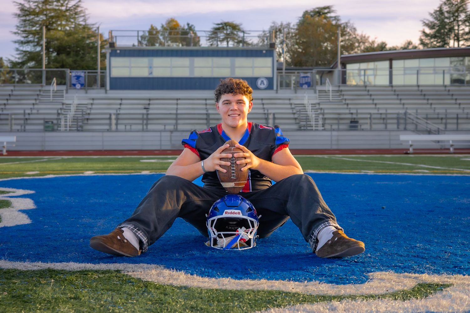 Analy high school senior sitting at the 50 yard line with football in portrait by smc shots of Sonoma county