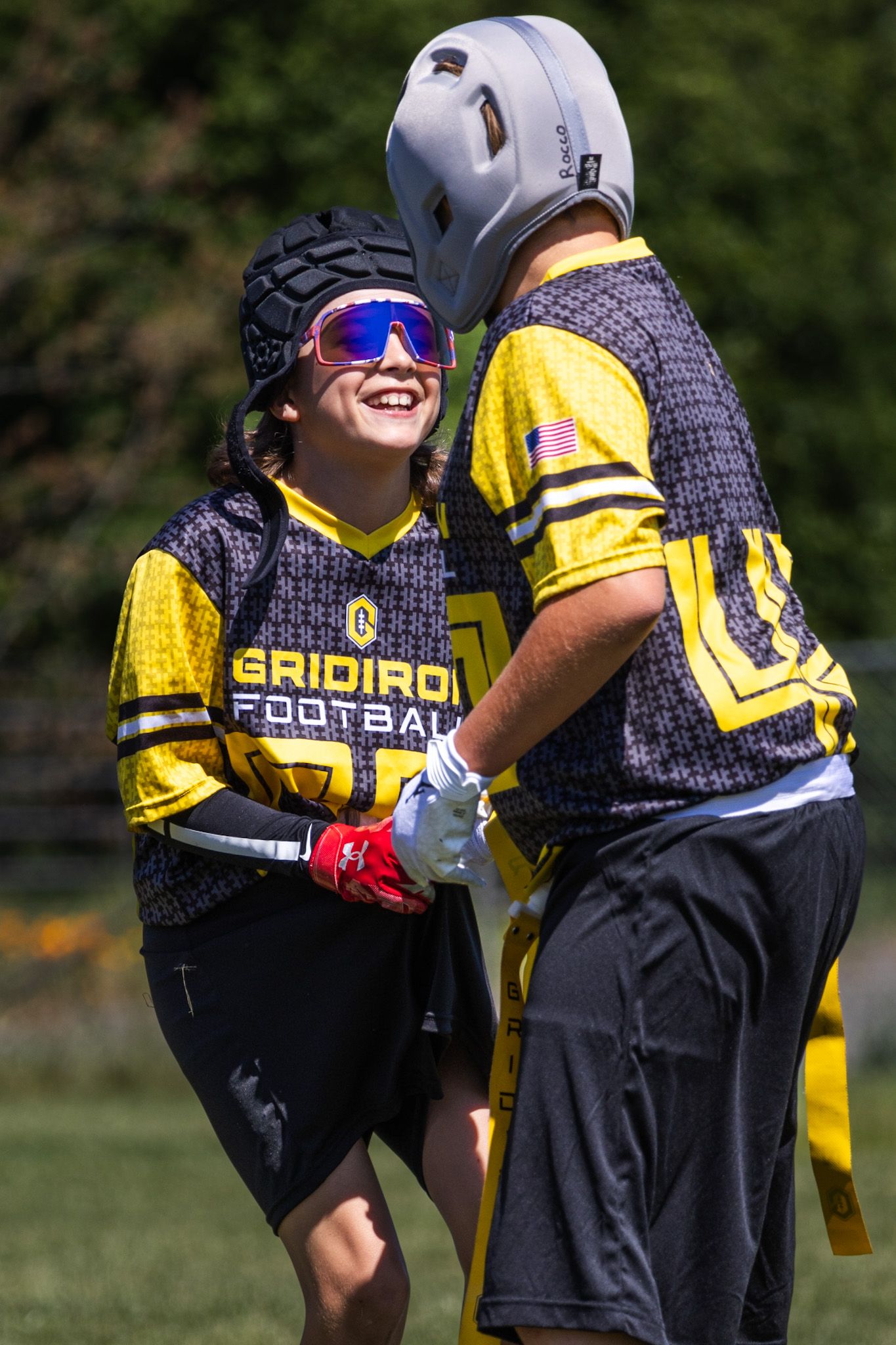 Flag Football player smiles at teammate with the ball in sports action shot by smc shots of Sonoma county