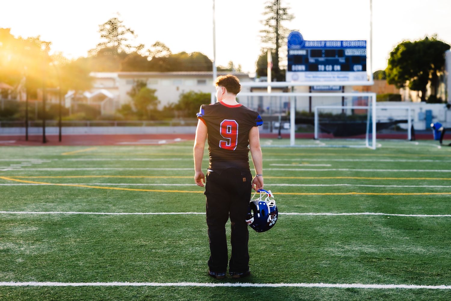 Analy high school senior looks into the sunset with football in portrait by smc shots of Sonoma county