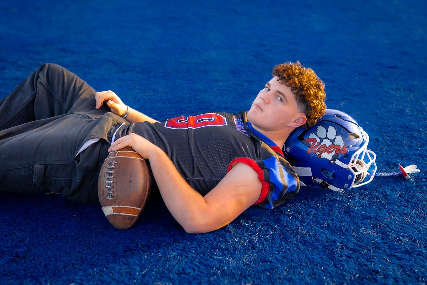Analy high school senior laying on the field with football in portrait by smc shots of Sonoma county