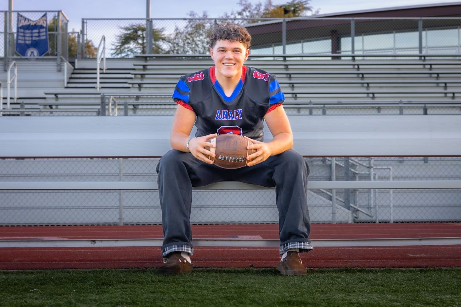 Analy high school senior smiling and sitting with football in portrait by smc shots of Sonoma county