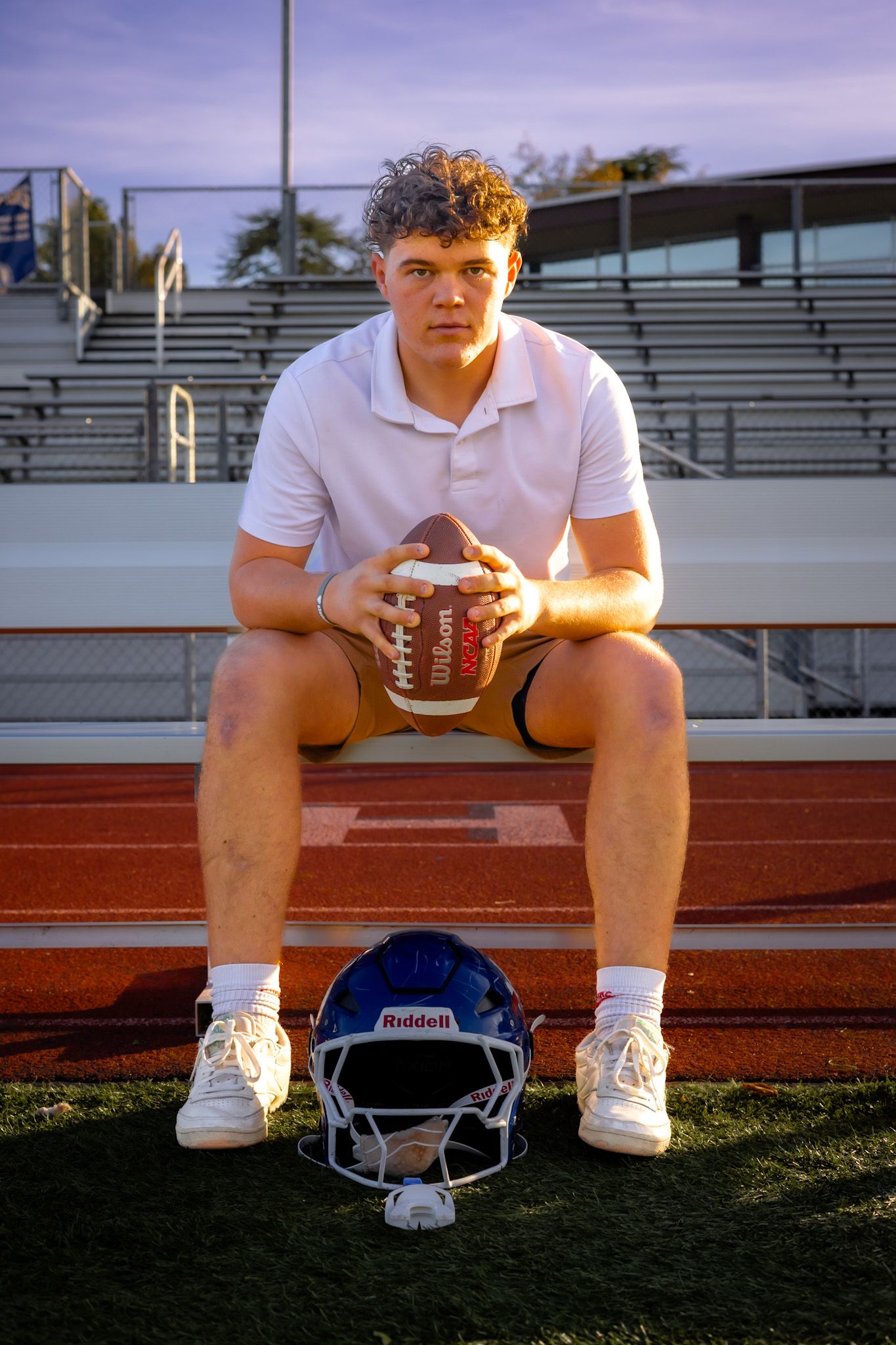 Analy high school senior looks serious sitting with football in portrait by smc shots of Sonoma county