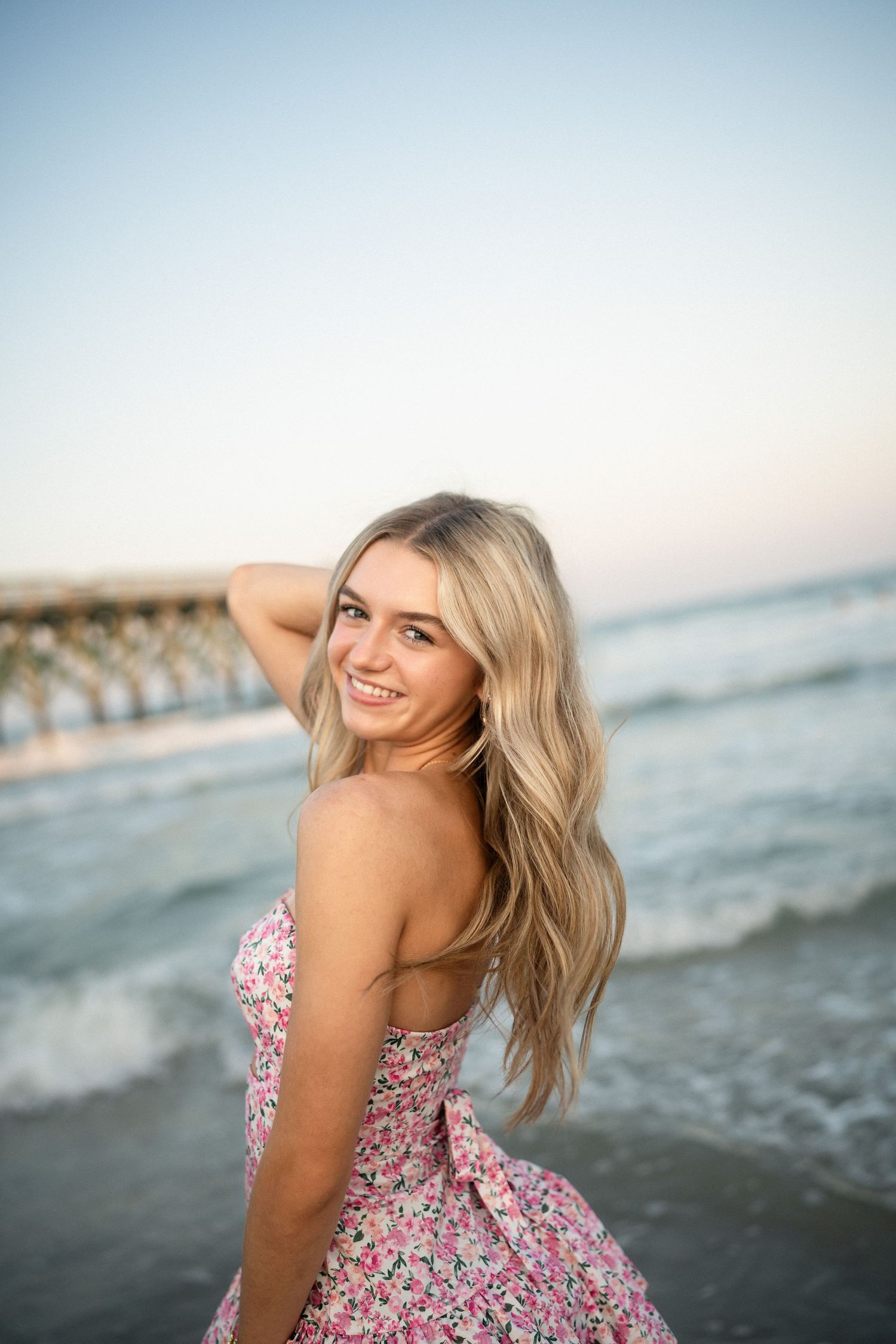 Senior portrait of Sydney at Wilmington, NC pier, showcasing a ocean backdrop during a beachside photo session