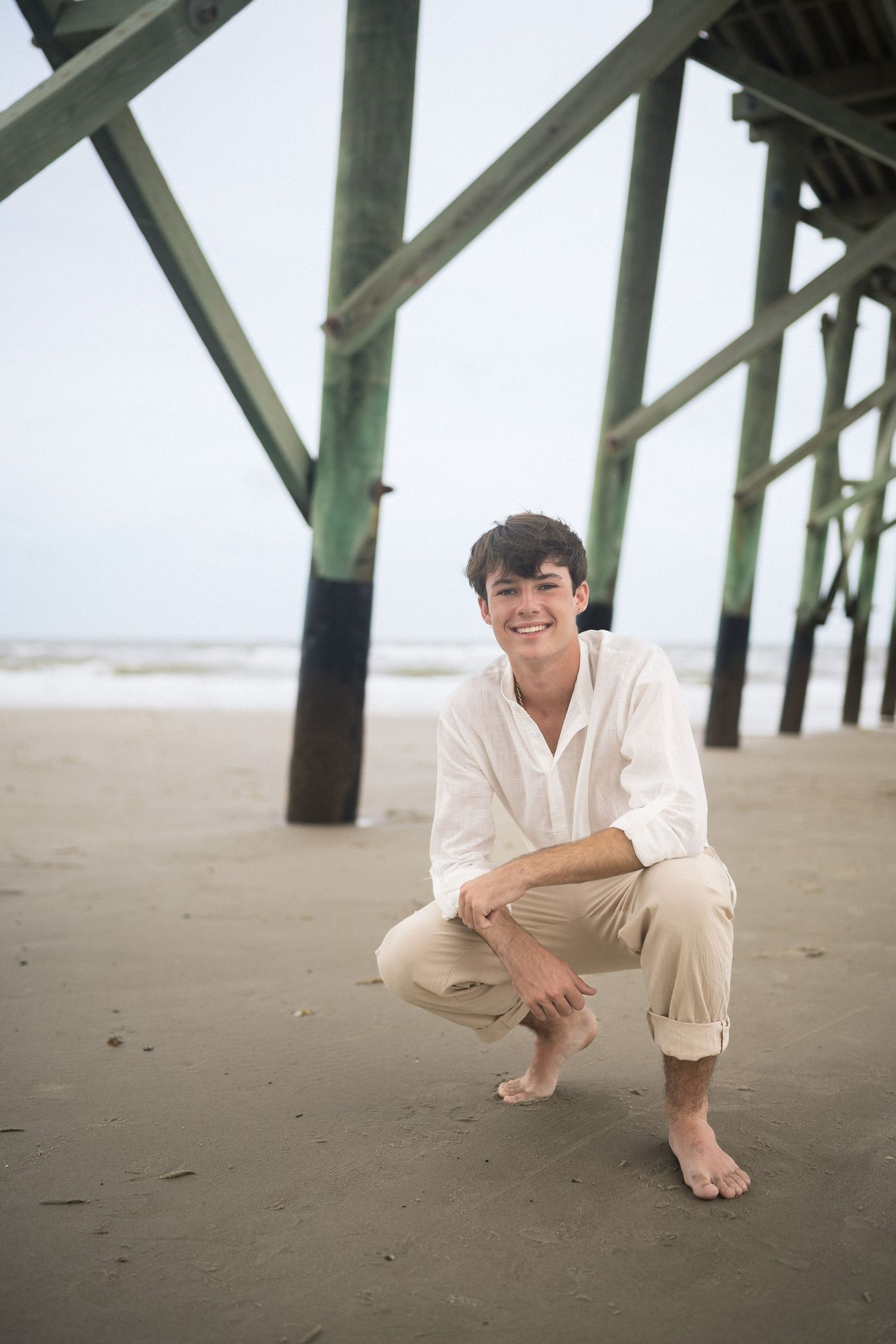 Senior boy portrait at Oak Island pier during beach session