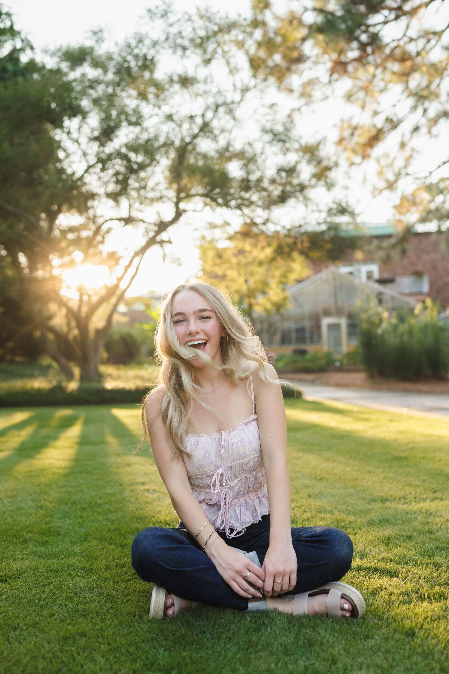 High school senior girl sitting in the grass at Sandhills Horticultural Gardens in Pinehurst, North Carolina during her senior photo session