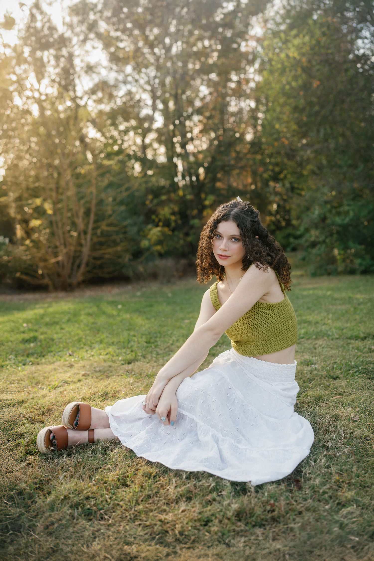 High school senior girl sitting on the grass at JC Raulston Arboretum in Raleigh, North Carolina.