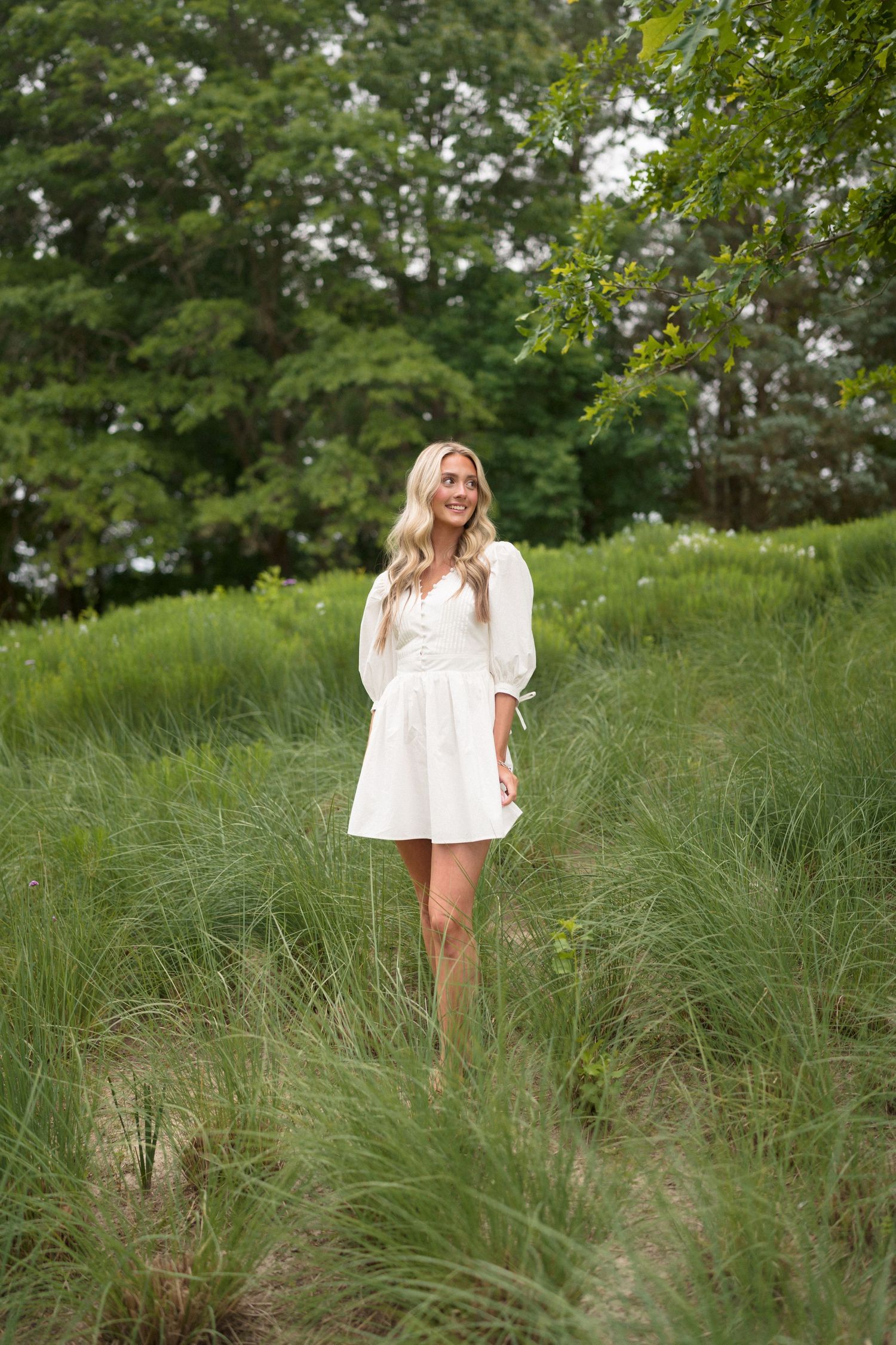 High school senior girl posing in a white dress at the North Carolina Museum of Art park in Raleigh.