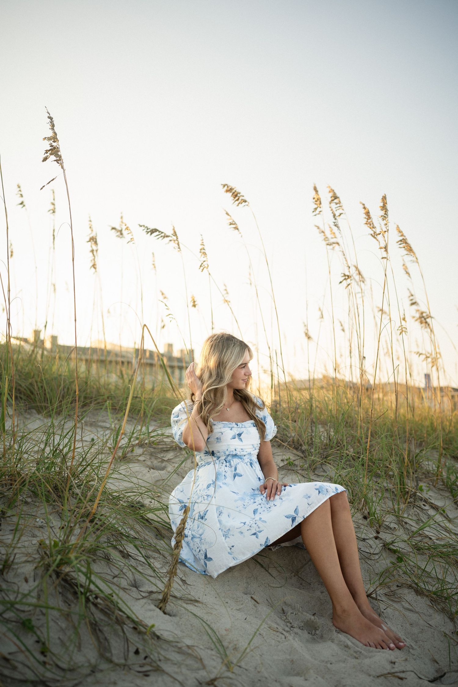 Sydney's senior photo session on Wilmington, NC beach, sitting in the sand during golden hour