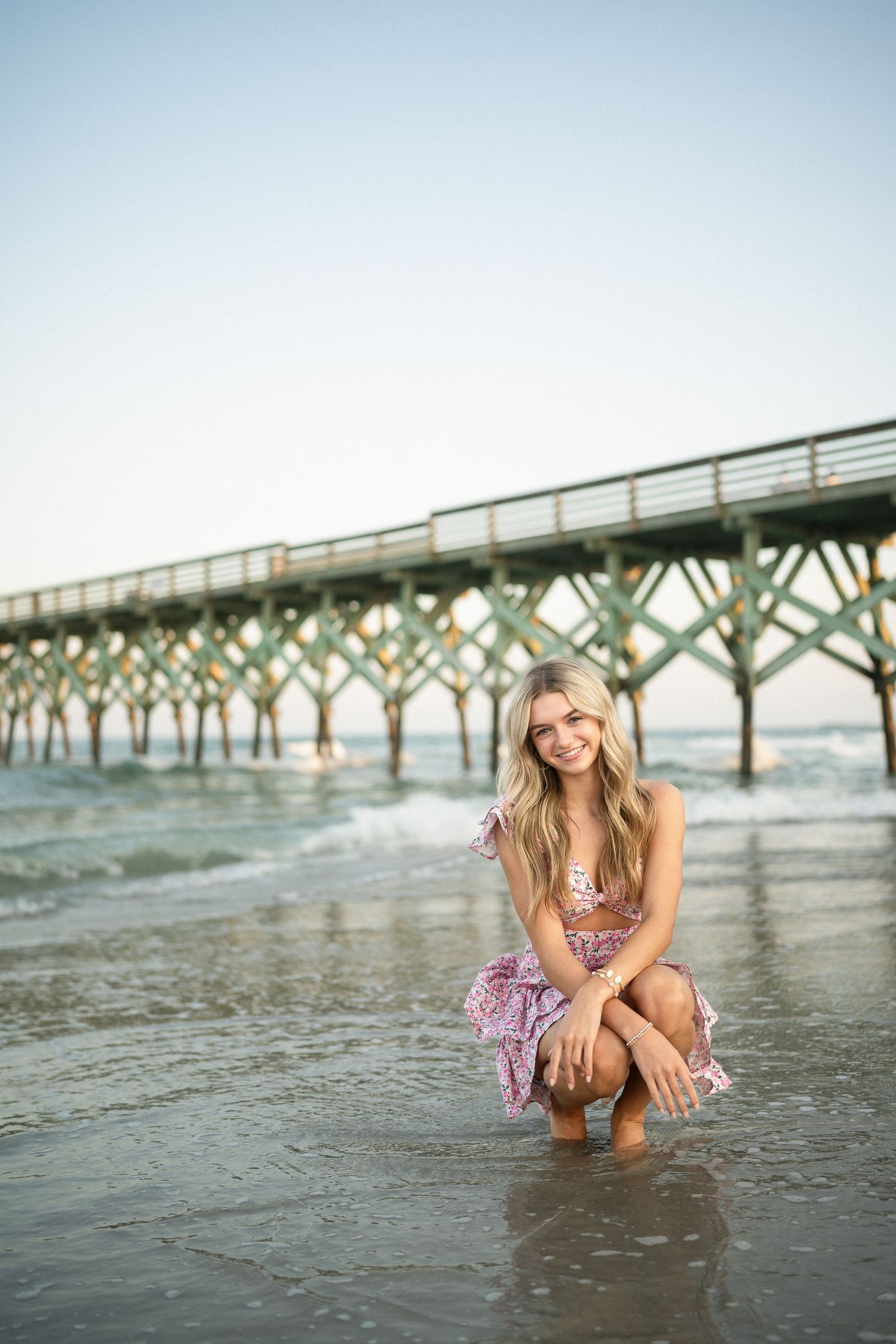 Senior portrait of Sydney at Wilmington, NC pier, showcasing a ocean backdrop during a beachside photo session