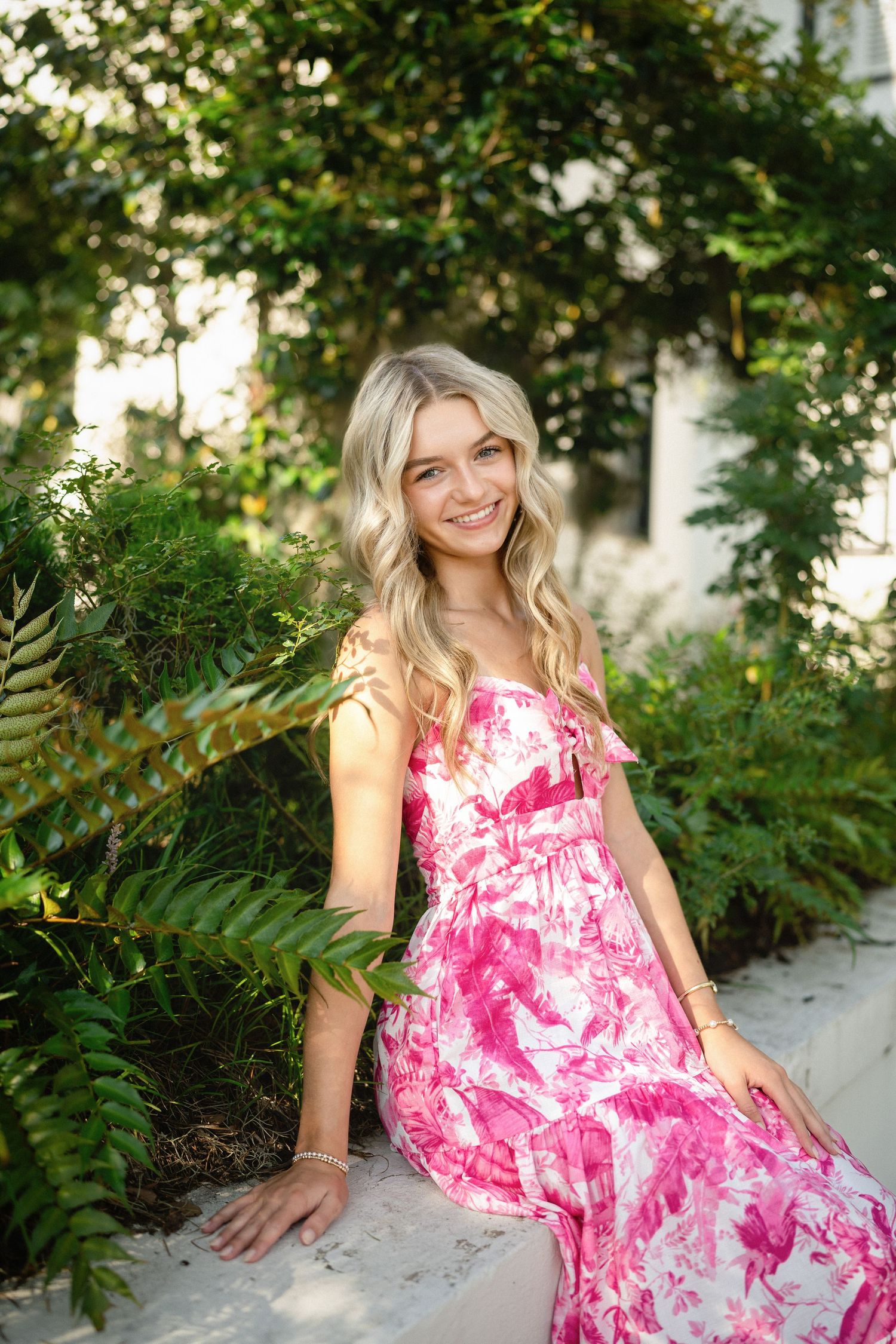 Senior photo of Sydney sitting in front of a stunning residence in Wilmington, NC, draped with Spanish moss.