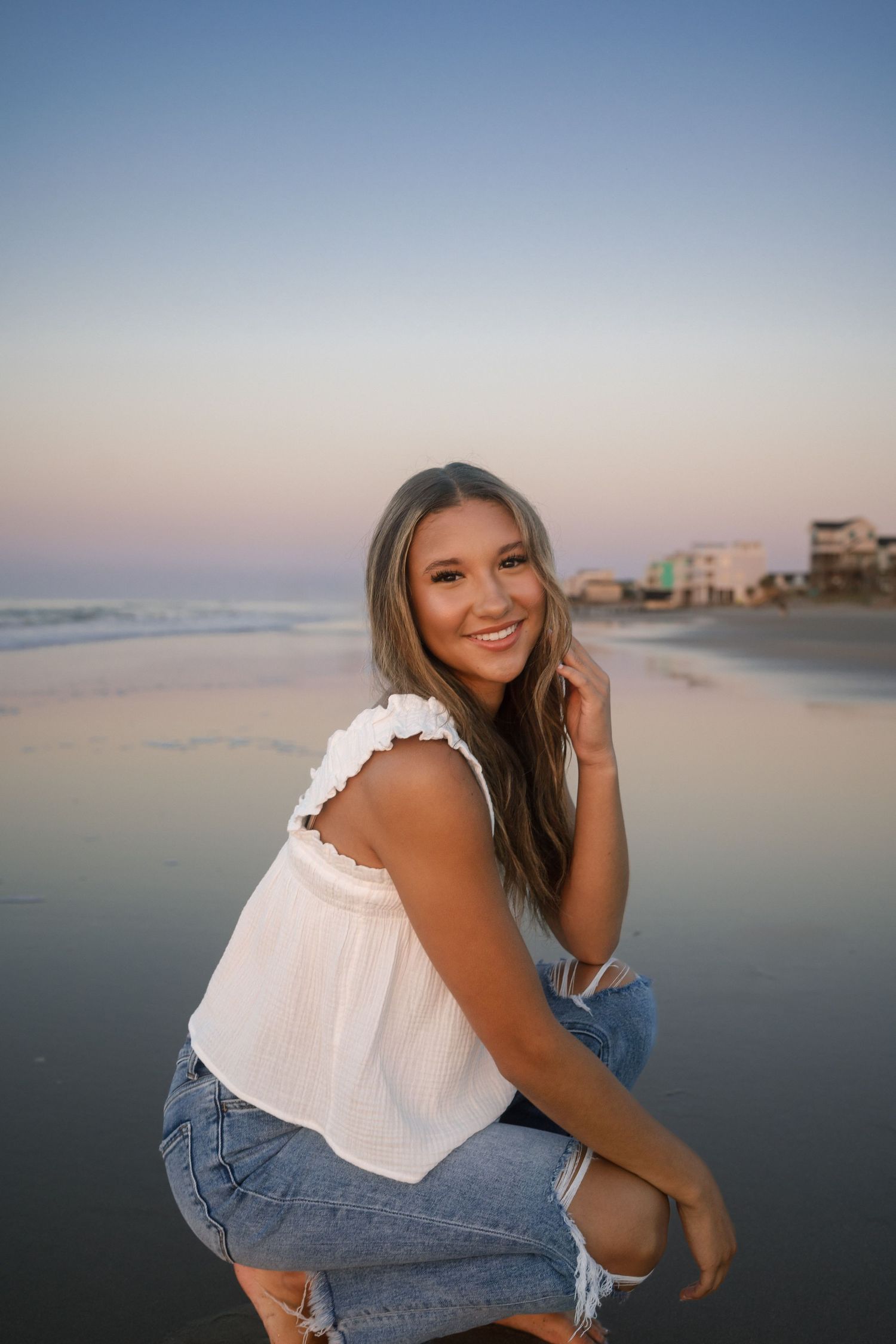 Sunrise senior portrait at Folly Beach with simple white tank and denim outfit.