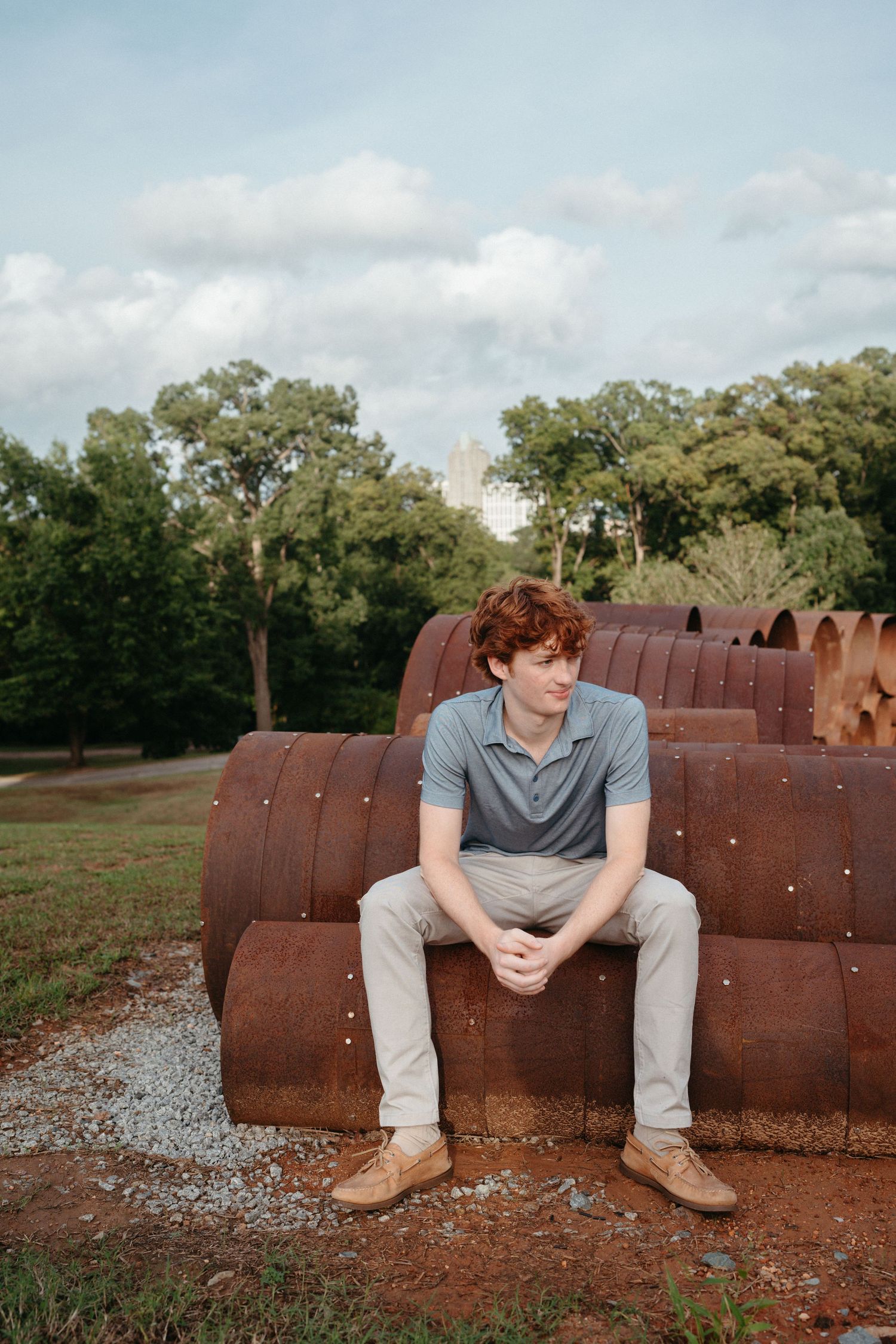 Senior boy sitting in pipe sculpture at Dorothea Dix Park in Raleigh