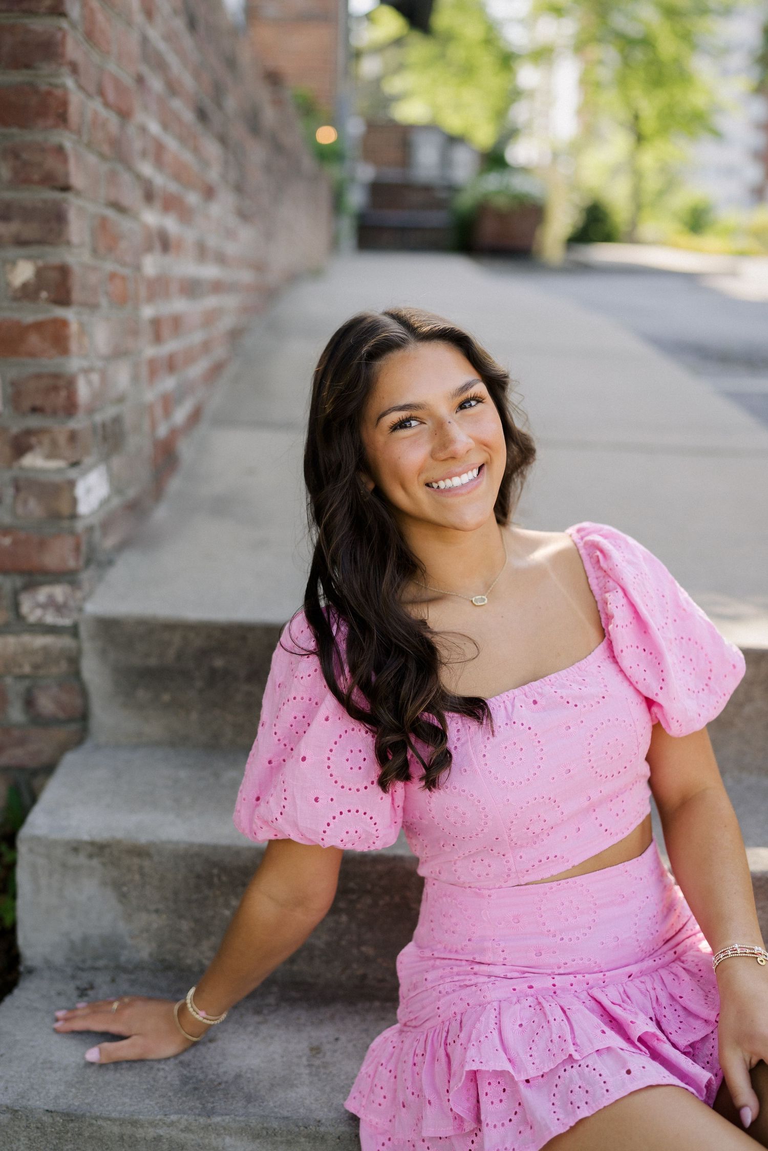 High school senior girl in a pink outfit sitting on stairs in downtown Raleigh, North Carolina.