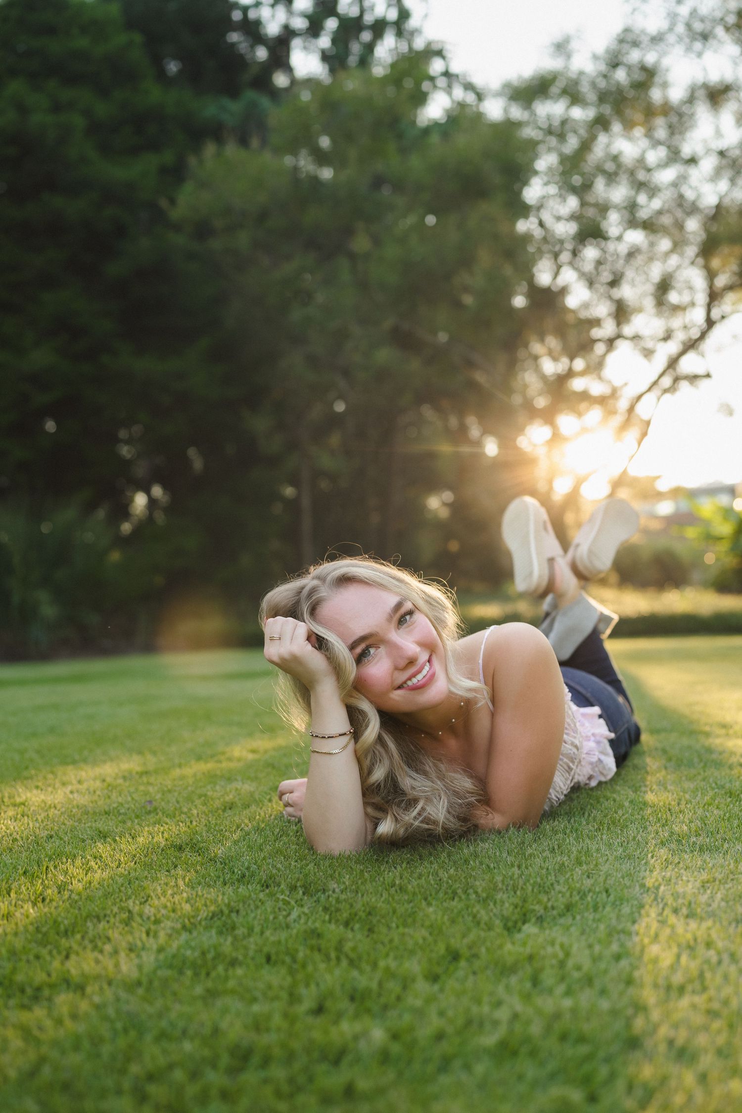 High school senior girl posing in the grass at Sandhills Horticultural Gardens in Pinehurst during her senior portraits.