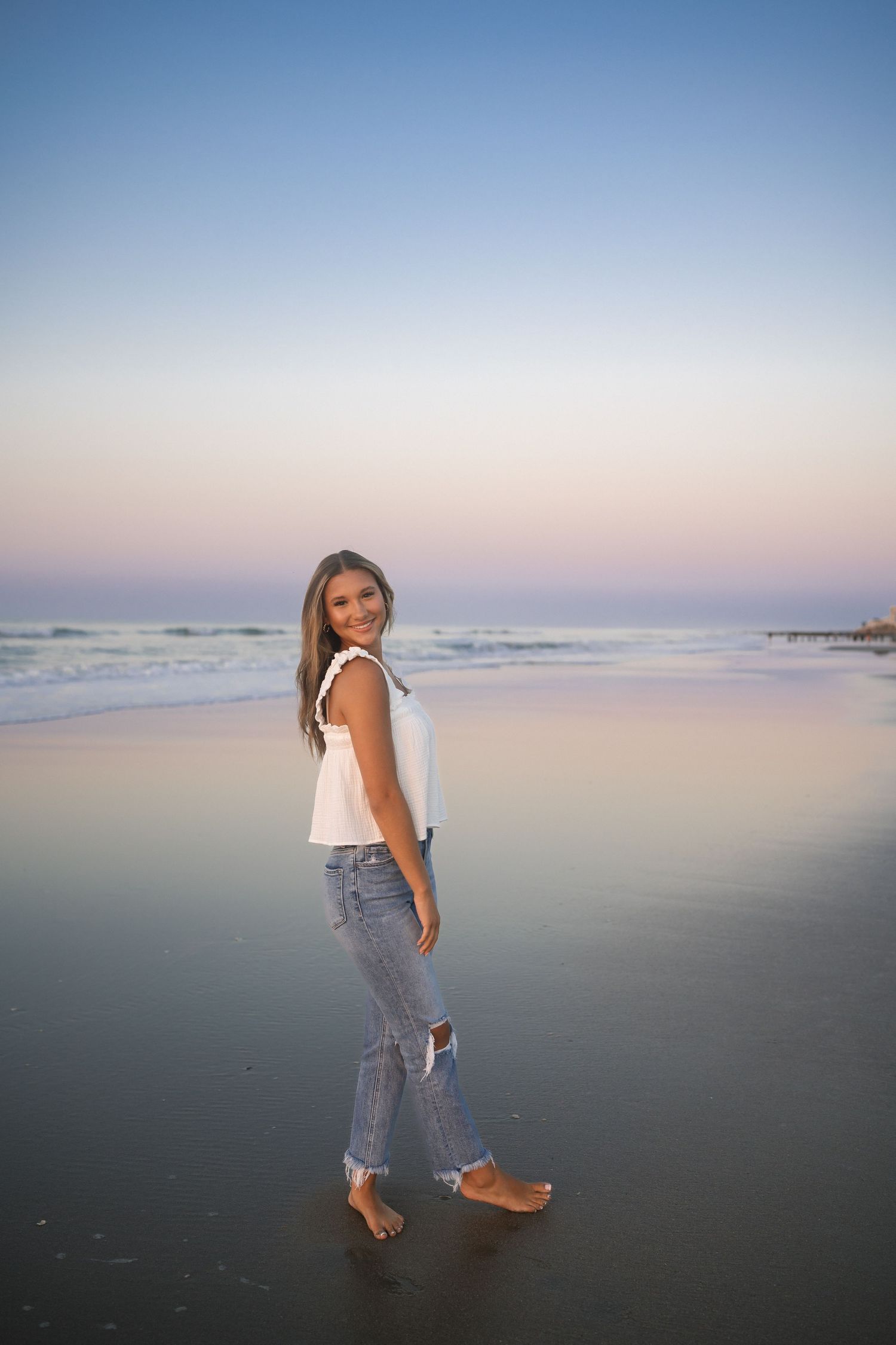 Sunrise senior portrait at Folly Beach with simple white tank and denim outfit.