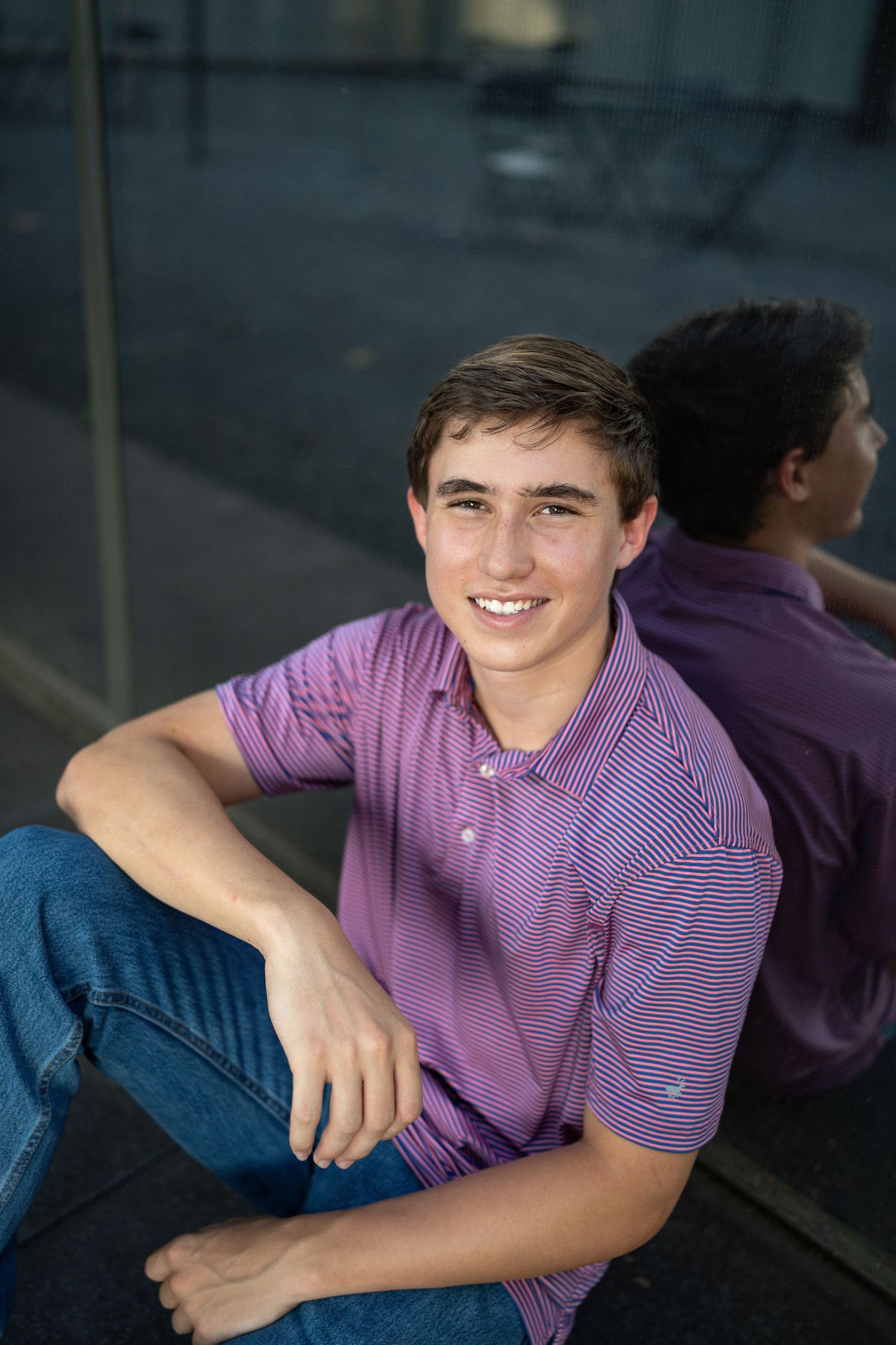 sitting wearing a purple polo shirt at NCMA for senior photos