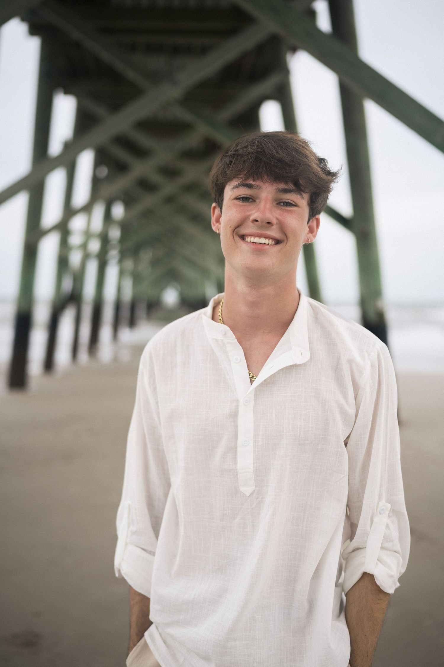 Portrait of Kason standing confidently beneath the Oak Island pier.