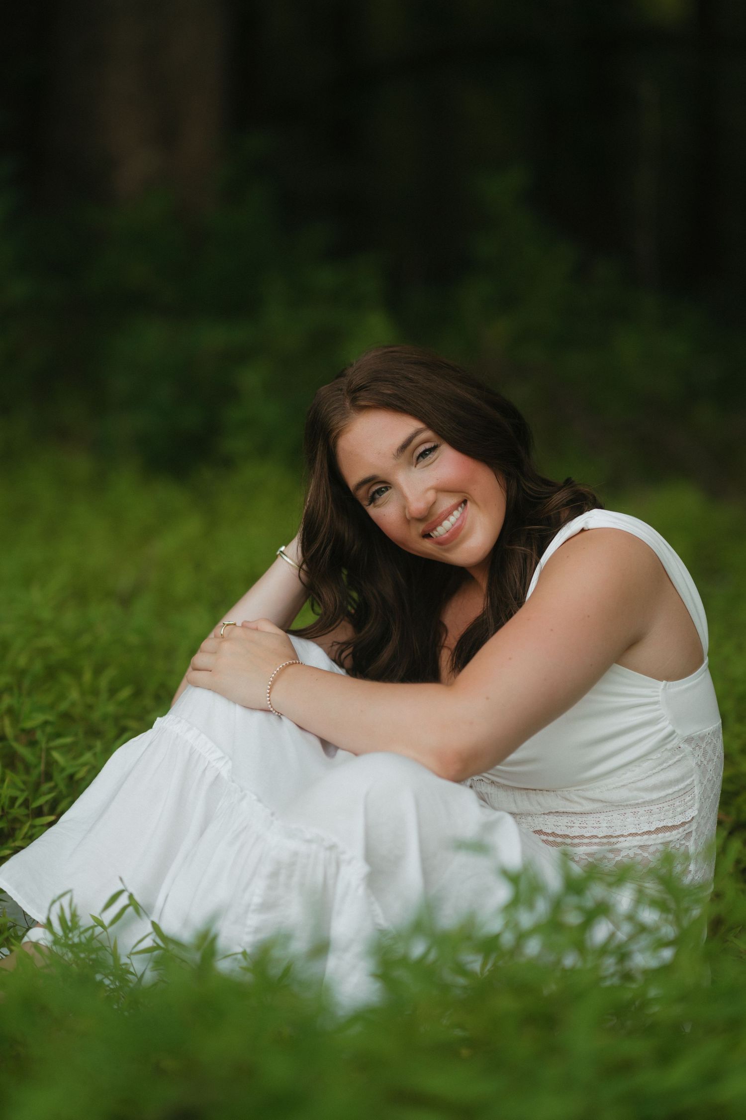 High school senior girl sitting in tall grass at Wilkerson Nature Preserve during a summer senior portrait session.