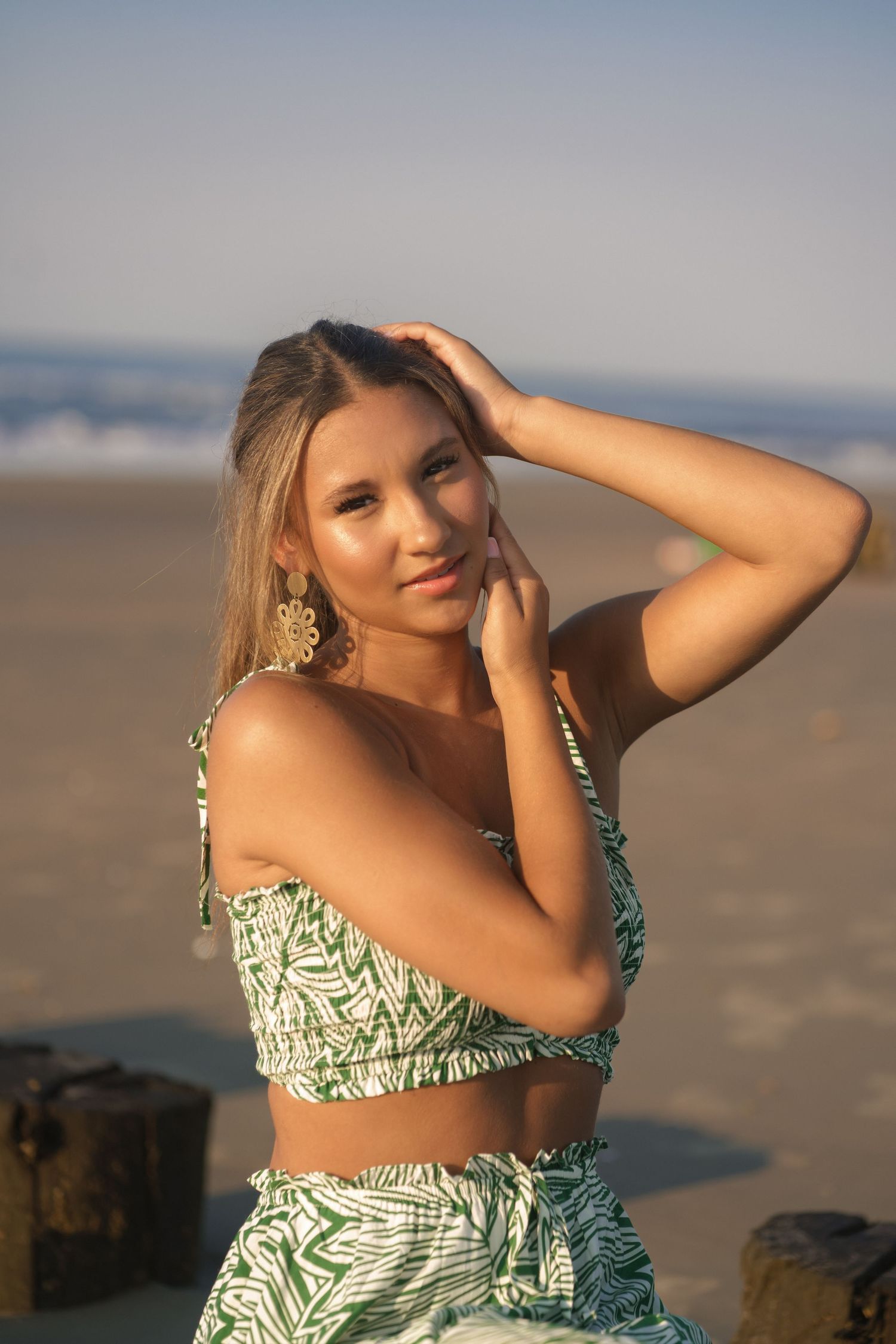 Sunrise senior photo at Folly Beach in a soft green floral two-piece maxi outfit.