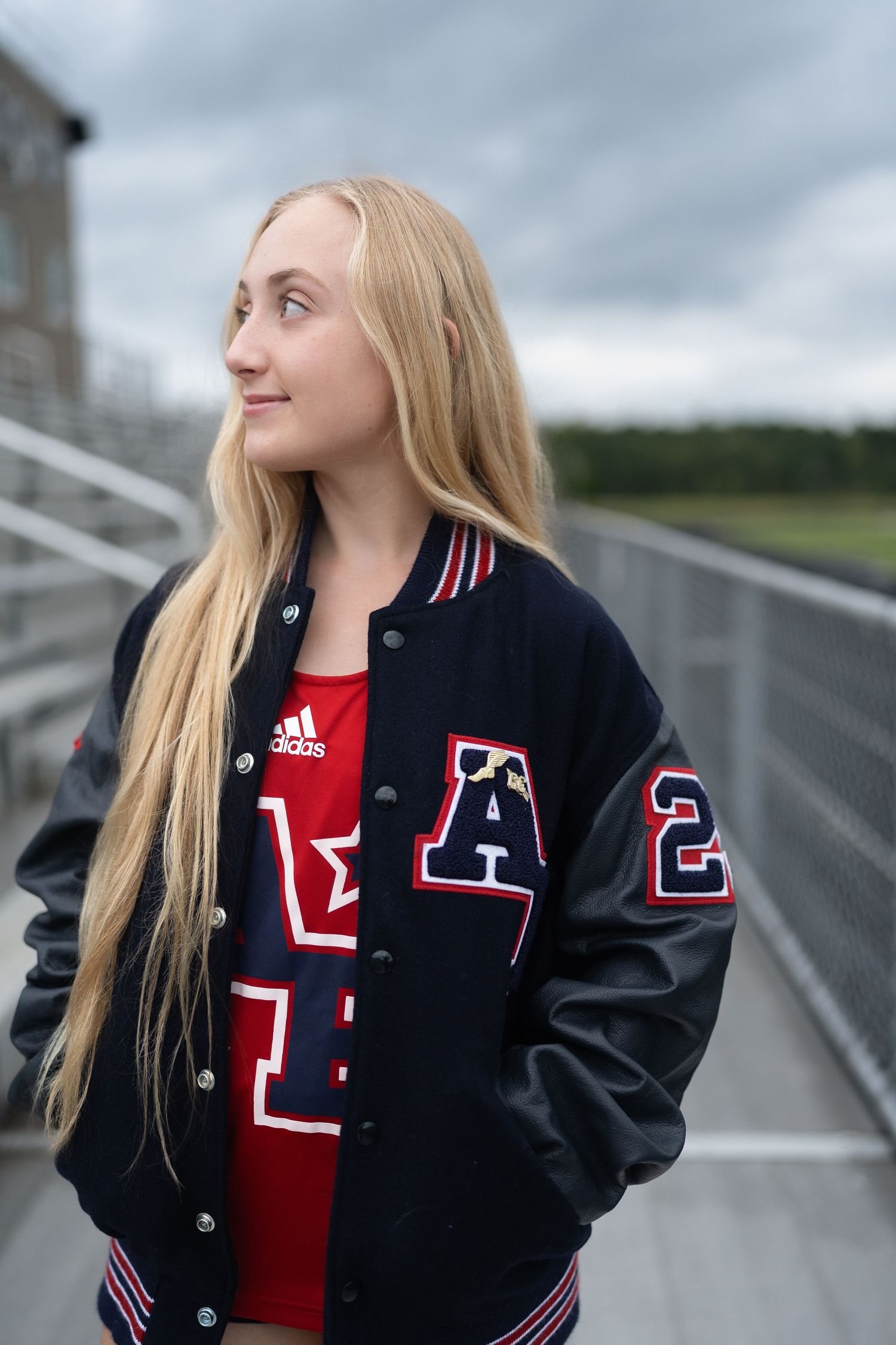 High school senior girl wearing a letterman jacket at Apex Friendship High School track in Apex, North Carolina.