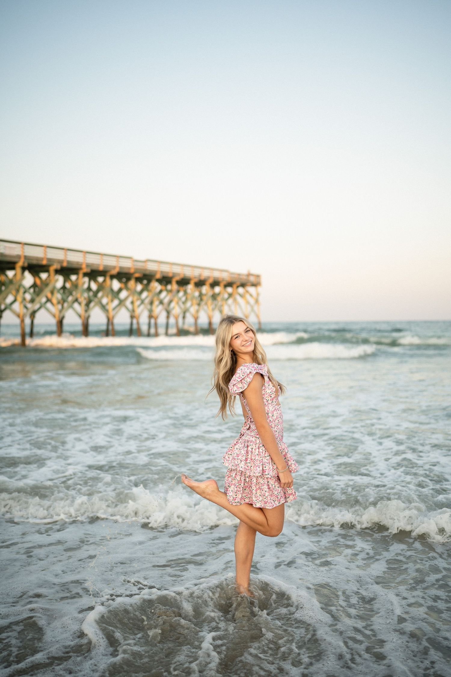 Senior portrait of Sydney at Wilmington, NC pier, showcasing a ocean backdrop during a beachside photo session