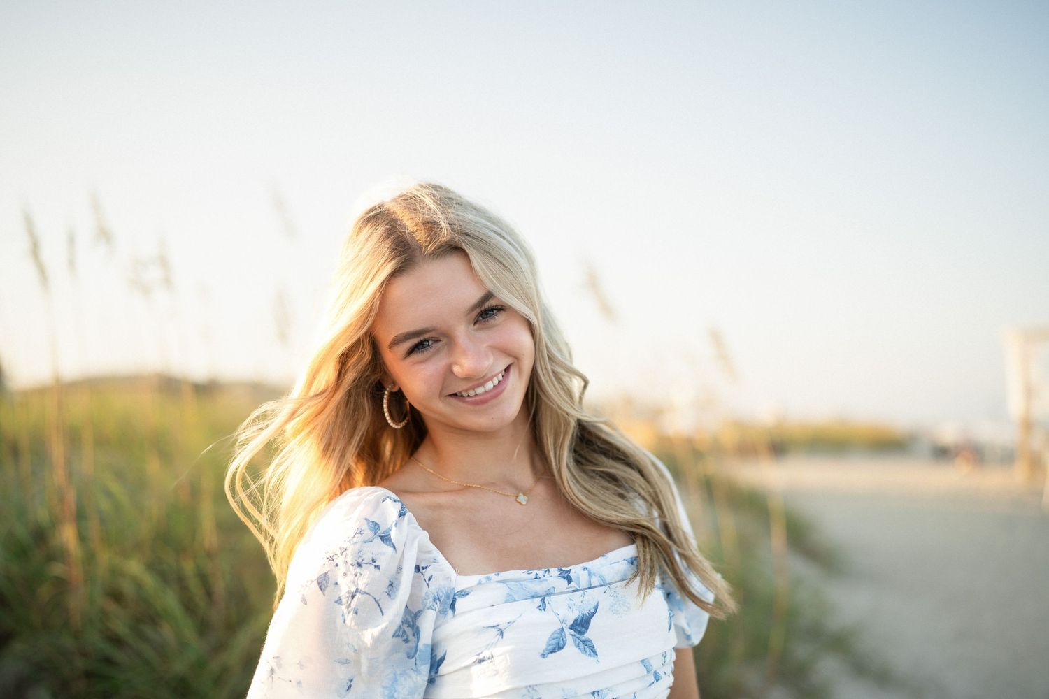 Sydney's senior photo session on Wilmington, NC beach, sitting in the sand during golden hour