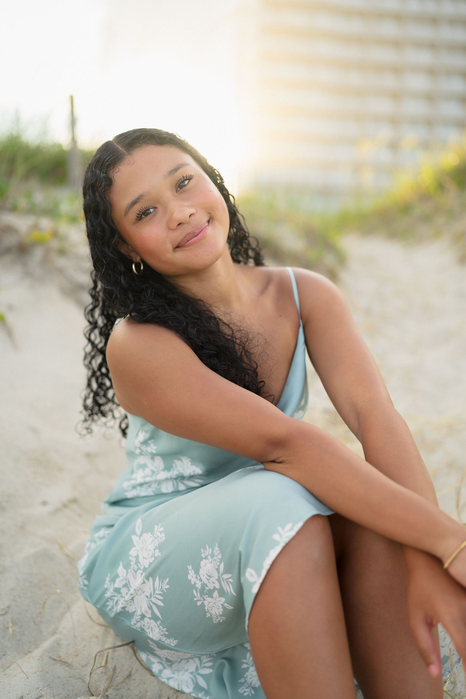 High school senior girl sitting in the sand during her senior portrait session at Carolina Beach, North Carolina.