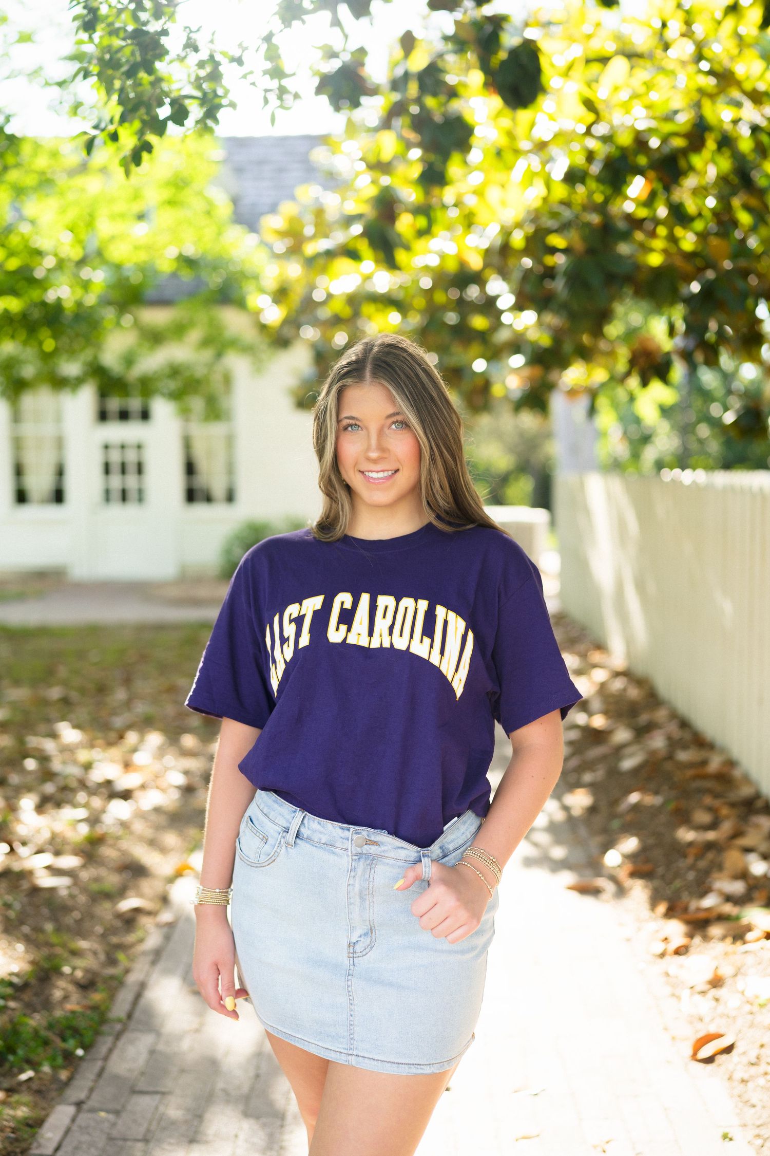 High school senior girl wearing an ECU shirt during her senior photo session at Historic Oak View County Park in Raleigh, North Carolina.