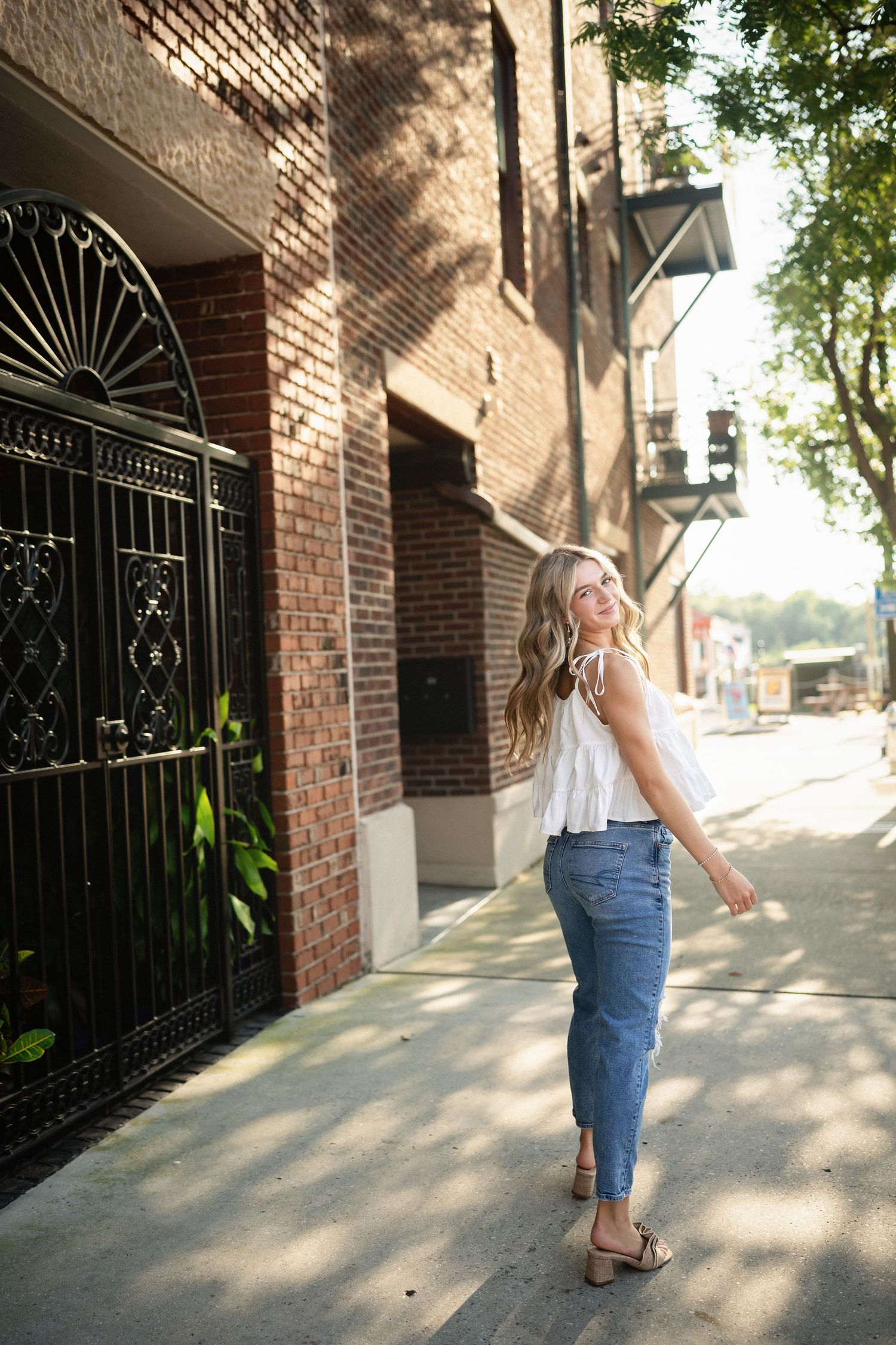Sydney's senior portrait at a gated home entrance in downtown Wilmington, NC, featuring elegant ironwork and greenery