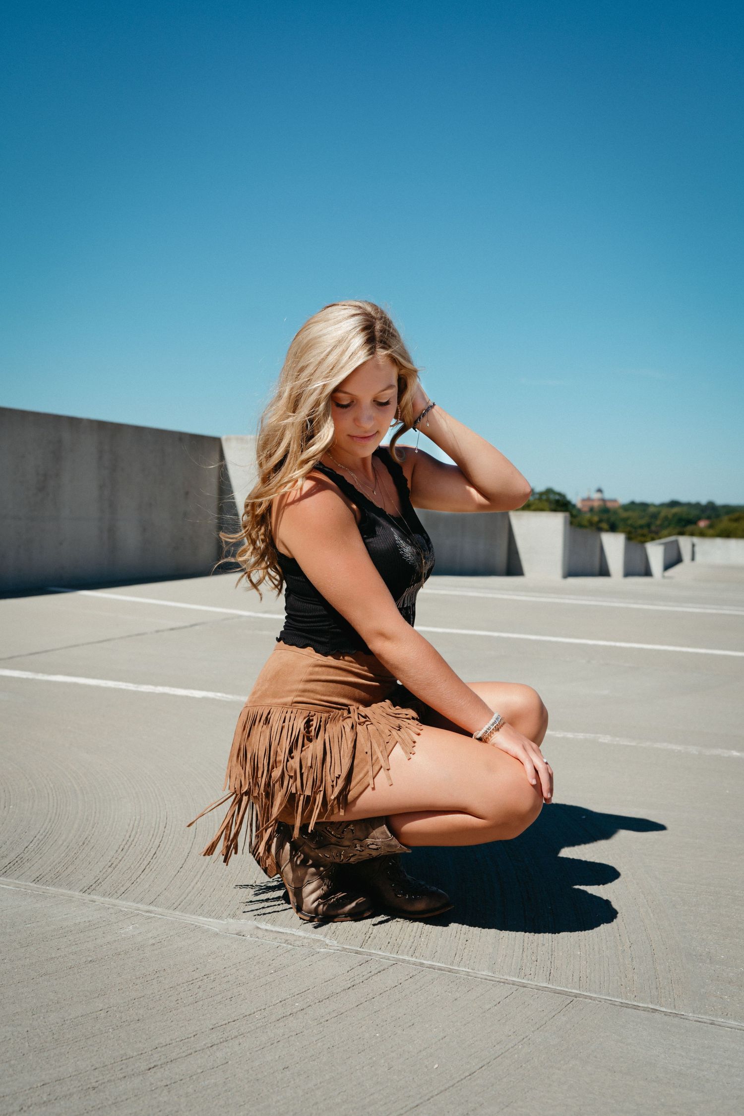 High school senior girl in a fringe skirt posing on a parking deck in downtown Raleigh.