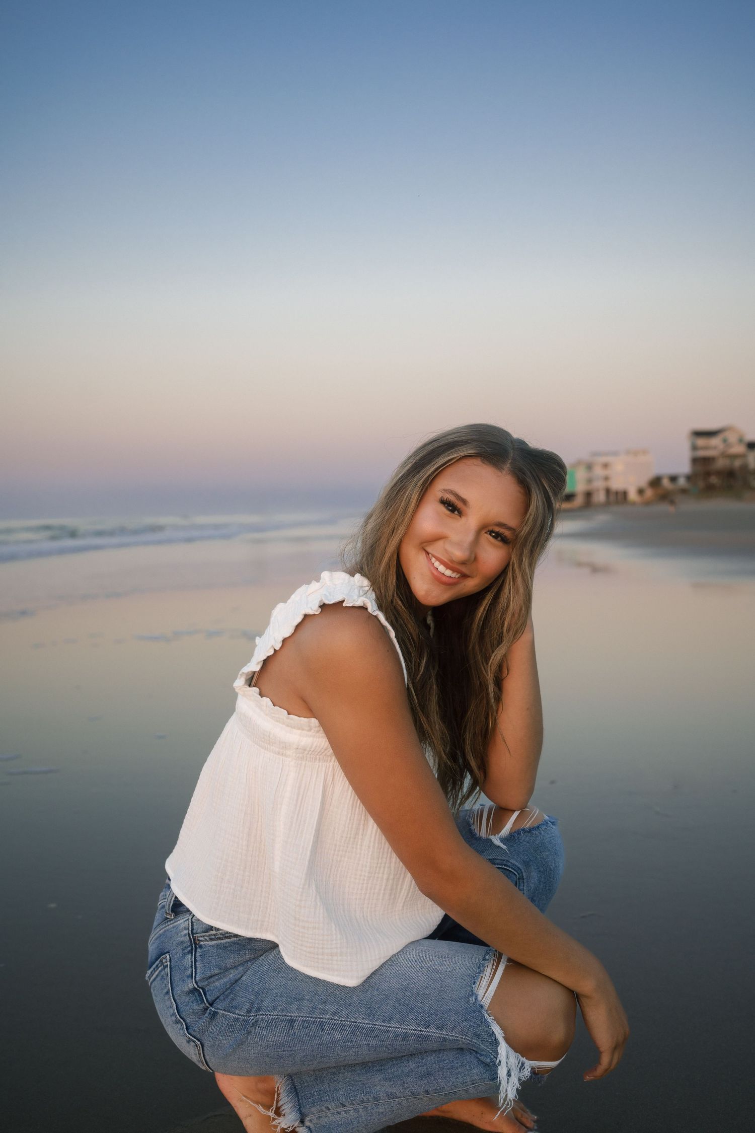 Sunrise senior portrait at Folly Beach with simple white tank and denim outfit.