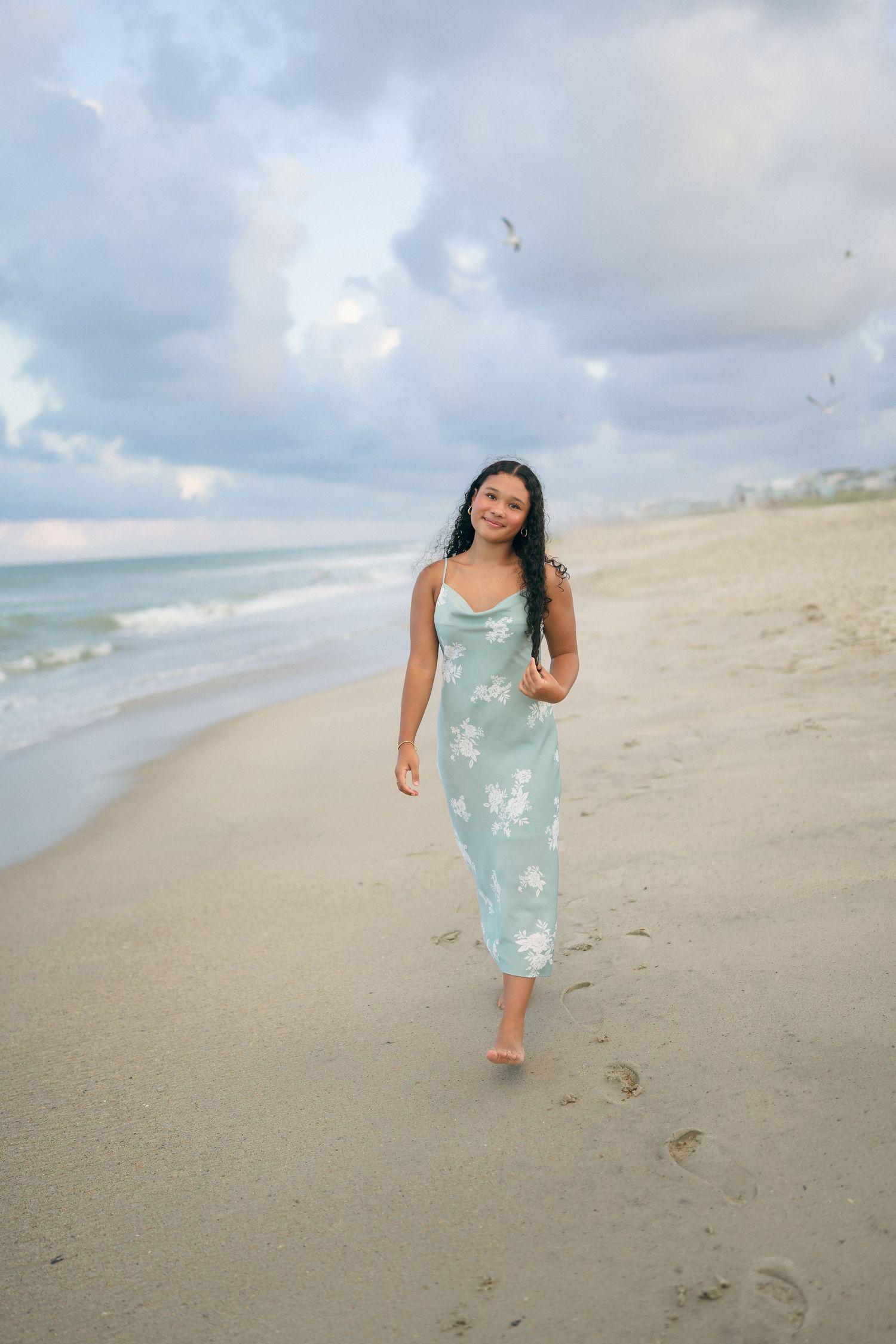 High school senior girl walking along the beach while playing with her hair at Carolina Beach, North Carolina.
