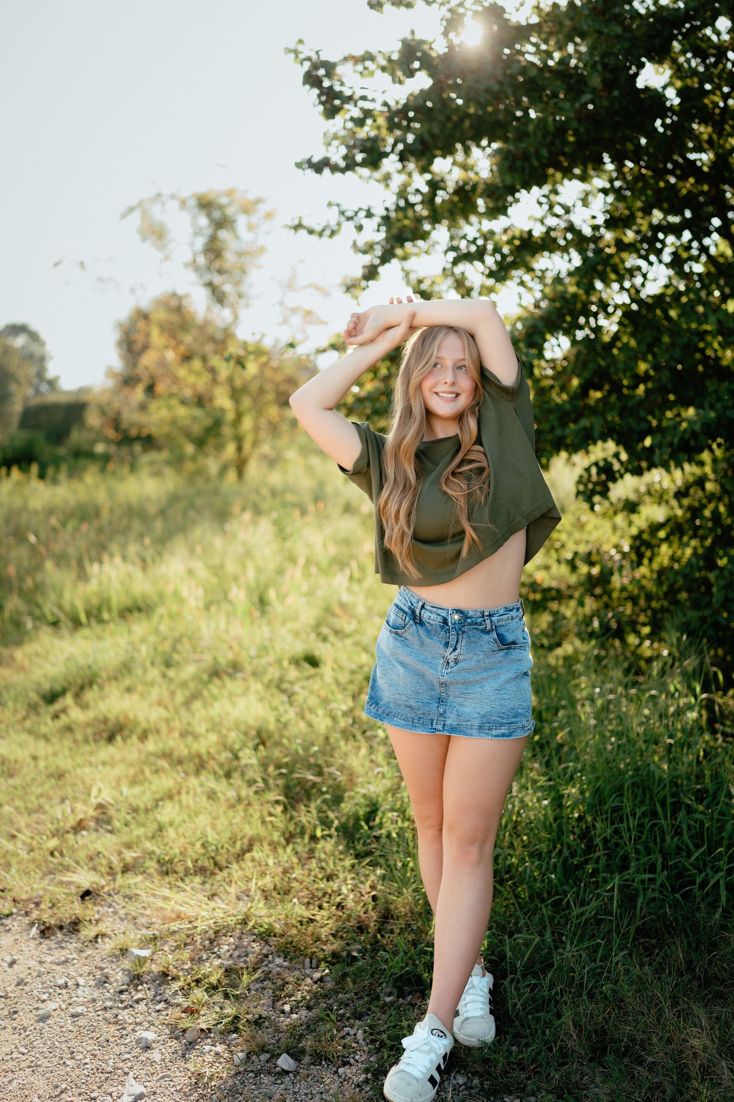High school senior girl posing with arms raised at Dix Park in Raleigh.