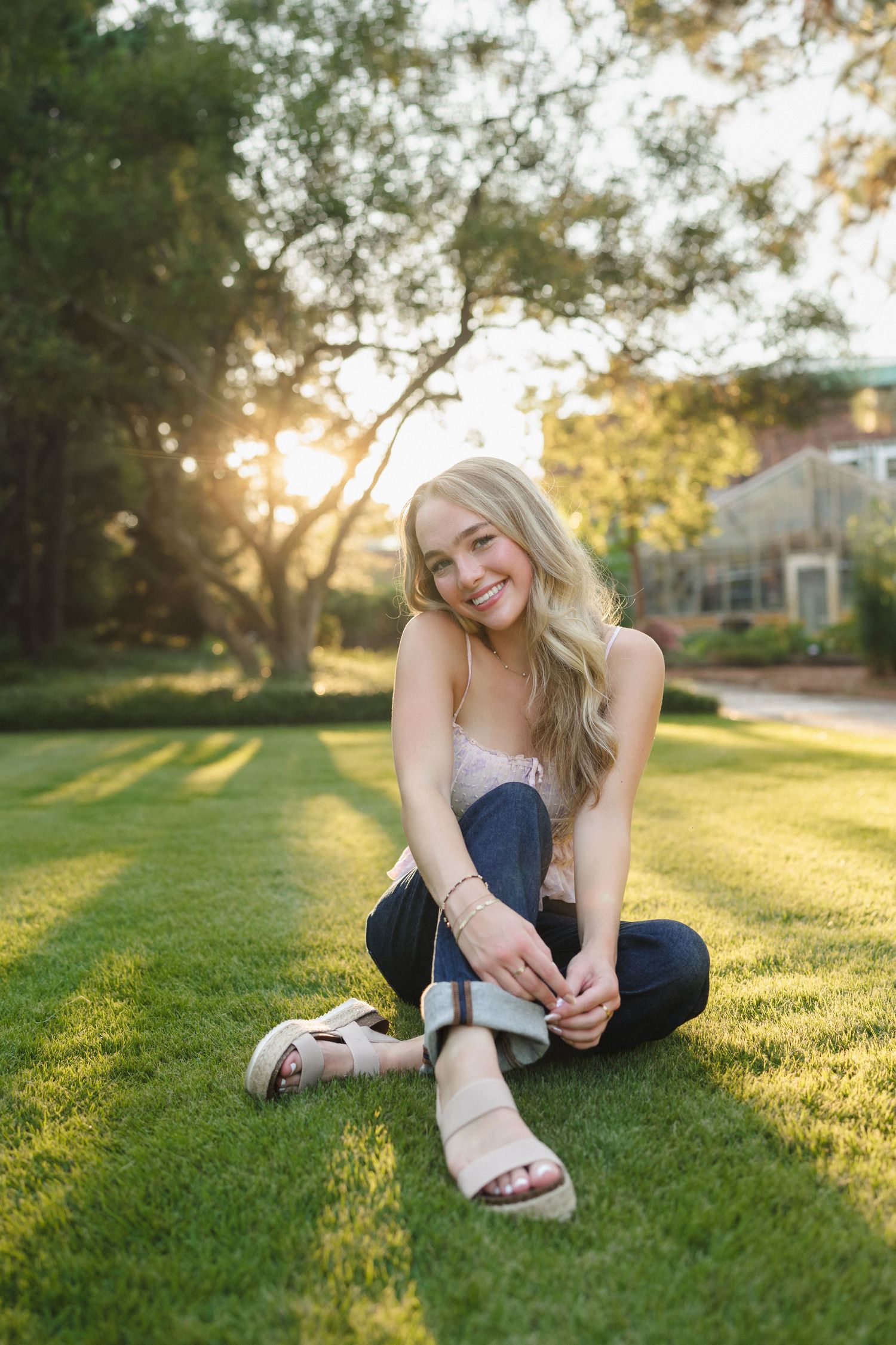High school senior girl relaxing in the grass during her senior session at Sandhills Horticultural Gardens in Pinehurst.