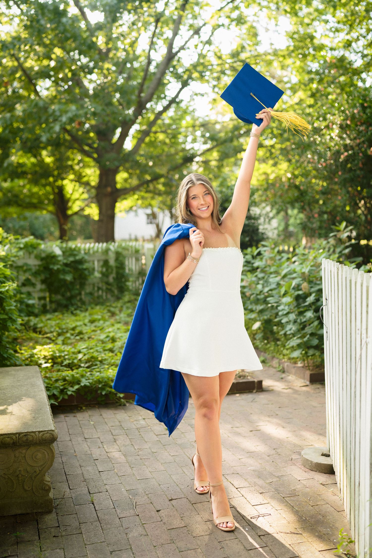 High school senior girl holding her cap and gown during her senior photo session at Historic Oak View County Park in Raleigh, North Carolina