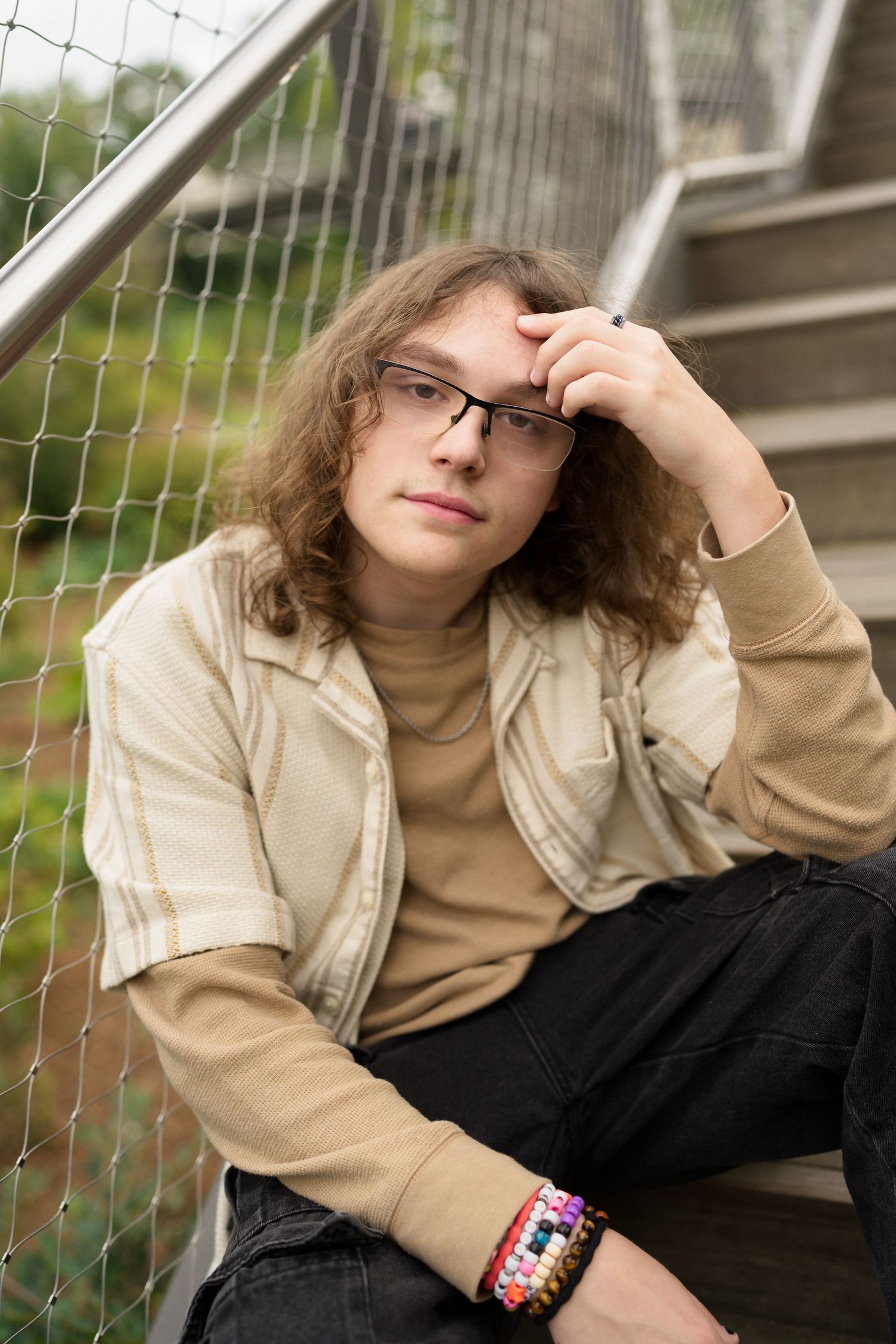 Close-up high school senior guy with long hair and glasses at Downtown Cary Park