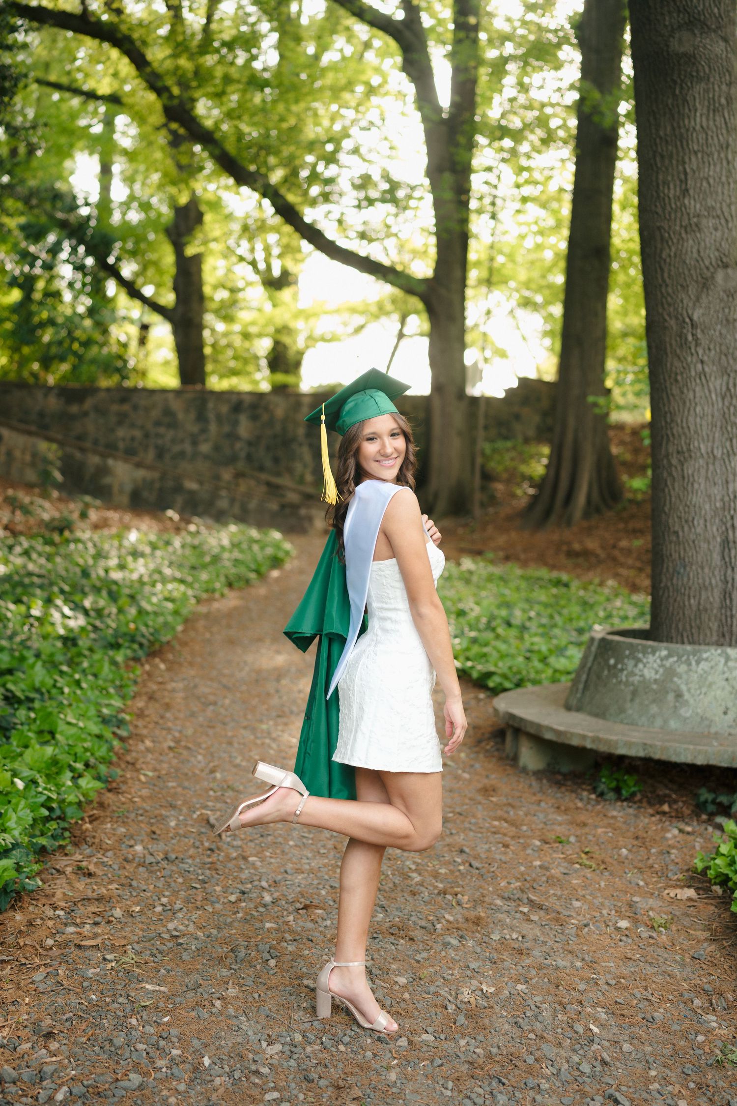 High school senior girl posing with her cap and gown at the Raleigh Rose Garden in Raleigh.