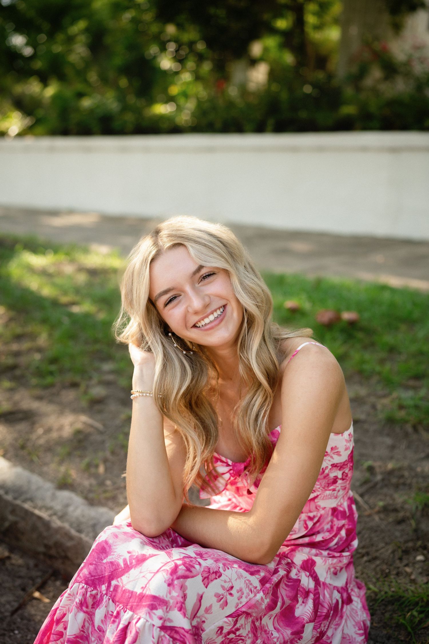 Senior photo of Sydney sitting on a curb in Wilmington, NC.